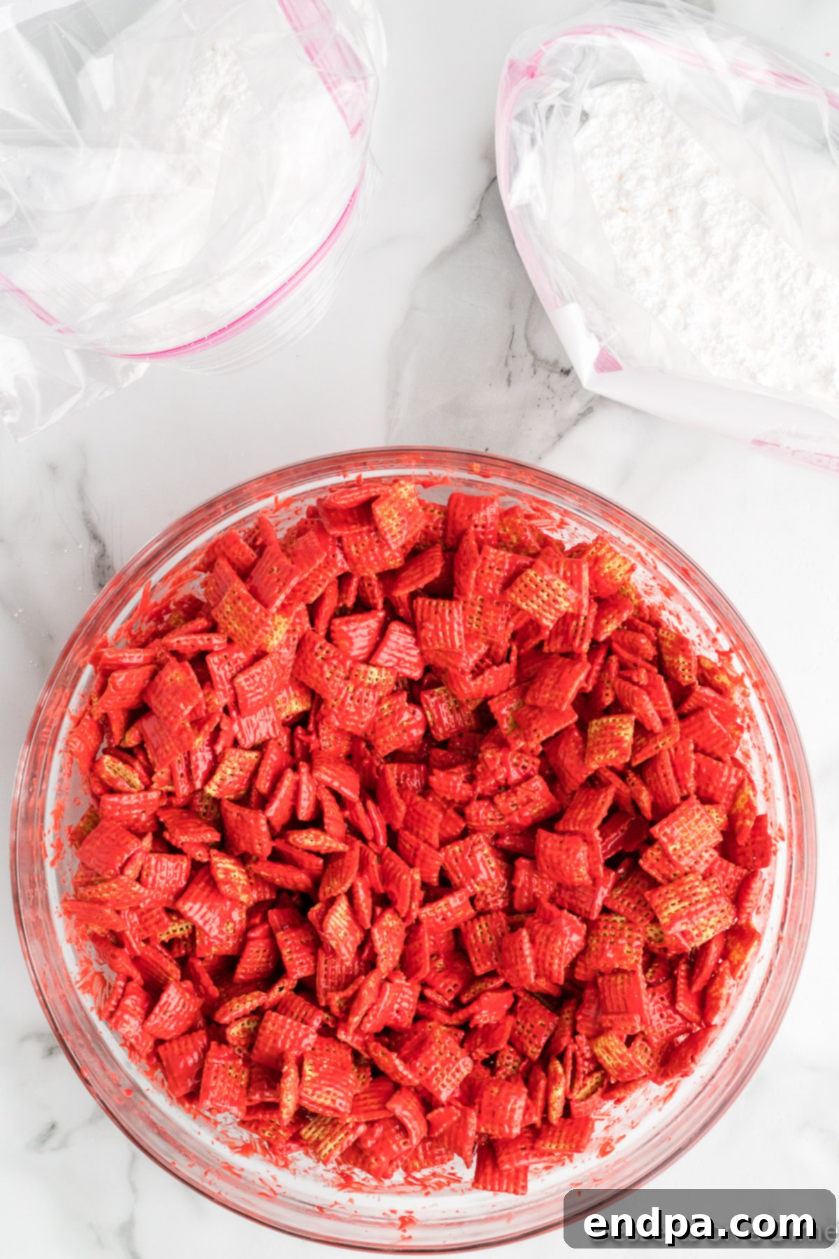 Chex cereal being coated with the melted peanut butter and candy mixture in a large mixing bowl.