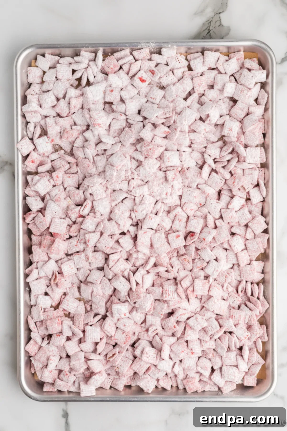 Coated cereal being shaken in a ziplock bag with powdered sugar, then spread on a baking sheet.
