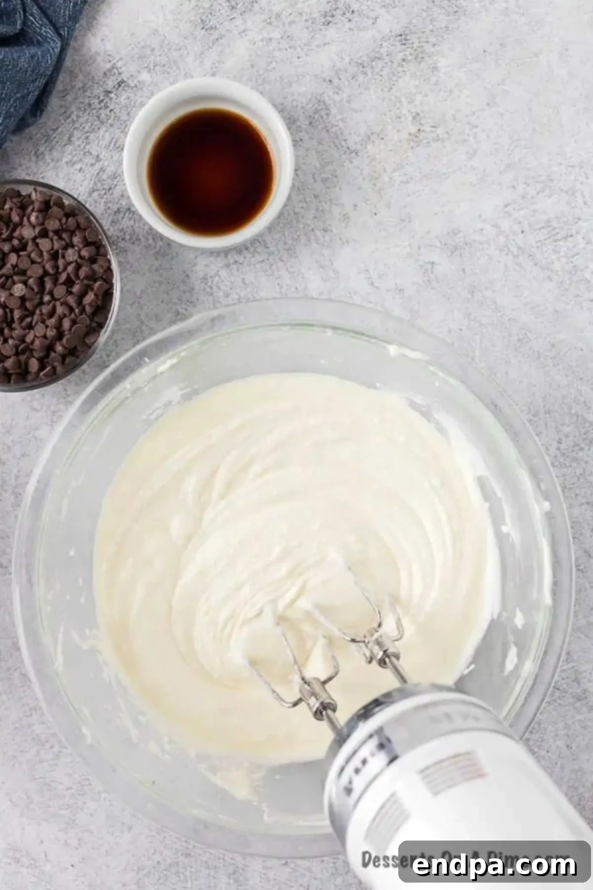 Cream cheese, ricotta, and powdered sugar being whipped together in a large mixing bowl to create a smooth base for the cannoli dip.