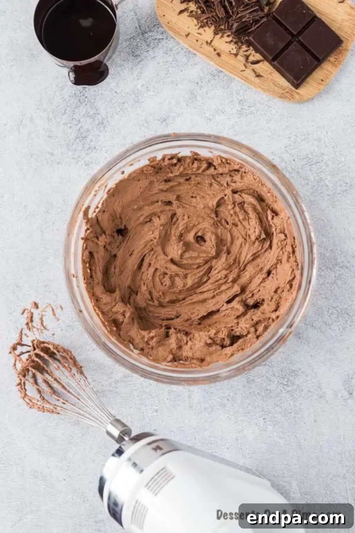 A mixing bowl filled with heavy whipping cream, cocoa powder, and powdered sugar, ready to be beaten into a fluffy topping.