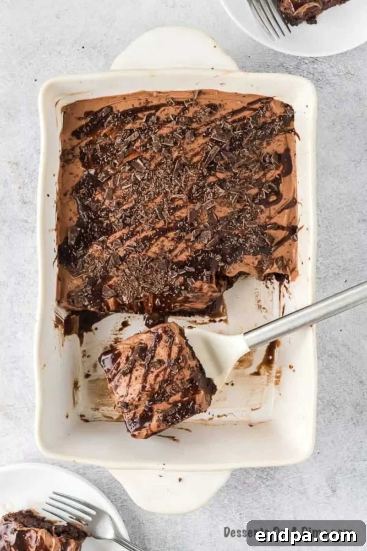 A hand reaching for a slice of the freshly made chocolate poke cake, ready to be enjoyed.