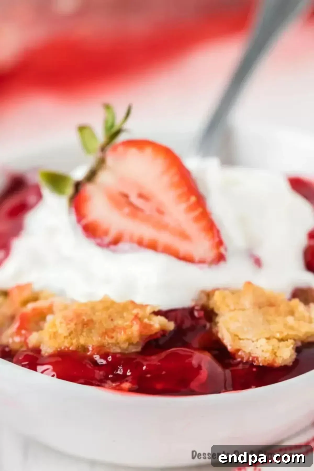One-Pan Strawberry Bliss 2 Strawberry Dump Cake in a bowl with whipped cream.