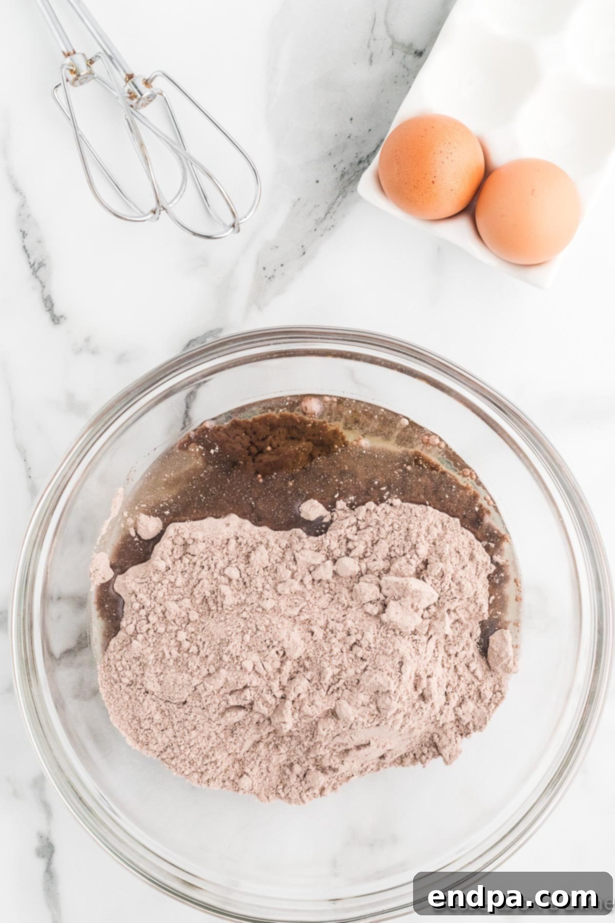 Cracked Cocoa Bliss 5 Eggs and vegetable oil being added to the cake mix in a bowl.