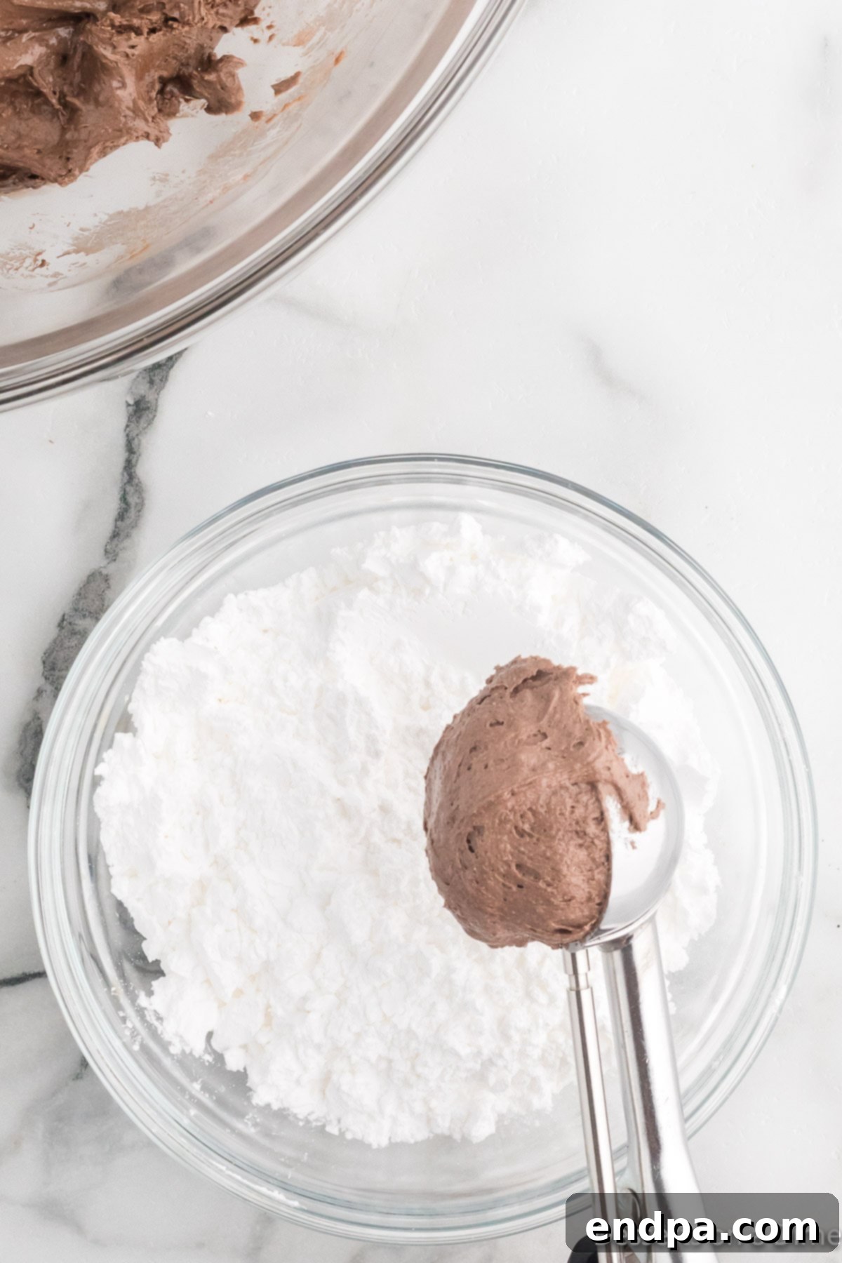 Cracked Cocoa Bliss 7 Scooping cookie dough and rolling it in powdered sugar.