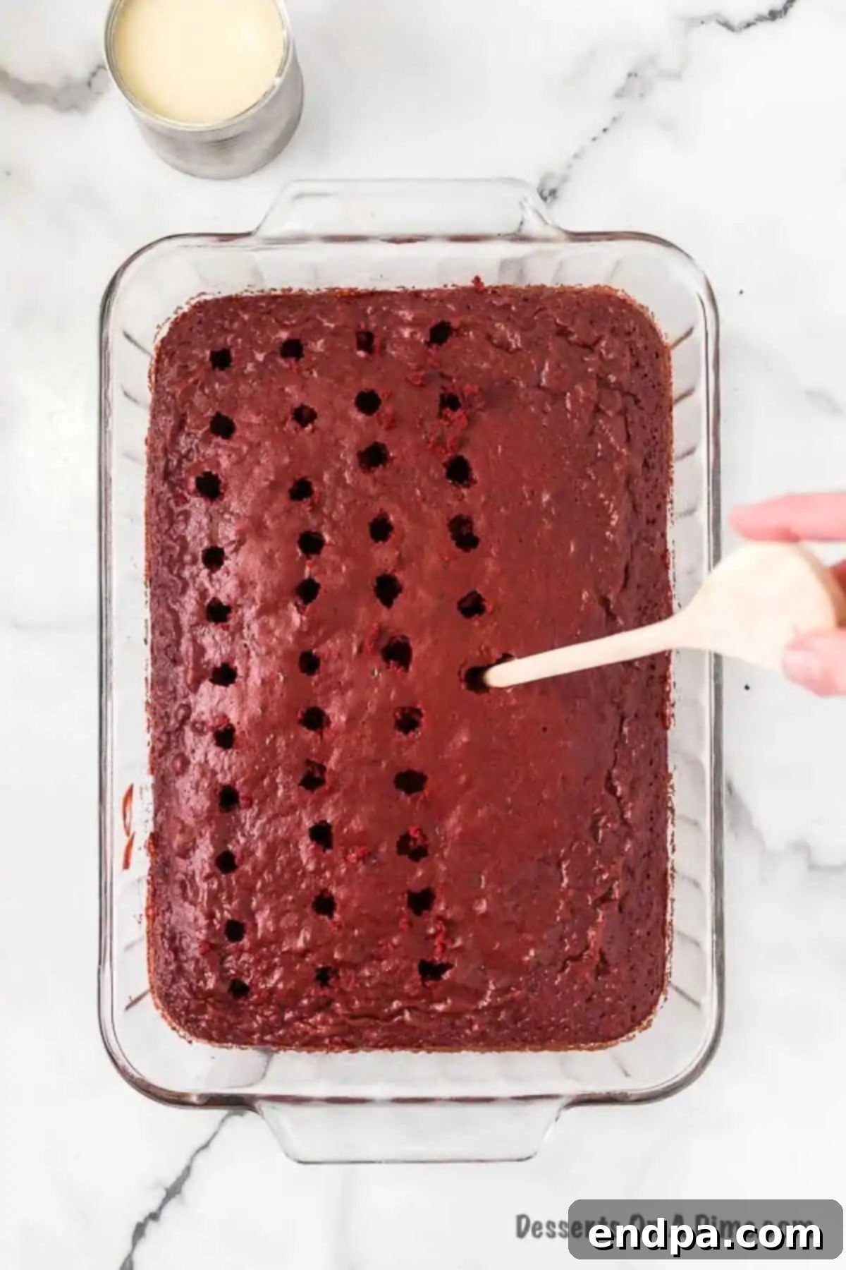 Red Velvet Infusion Cake 6 Baked cake with holes being poked all over its surface.