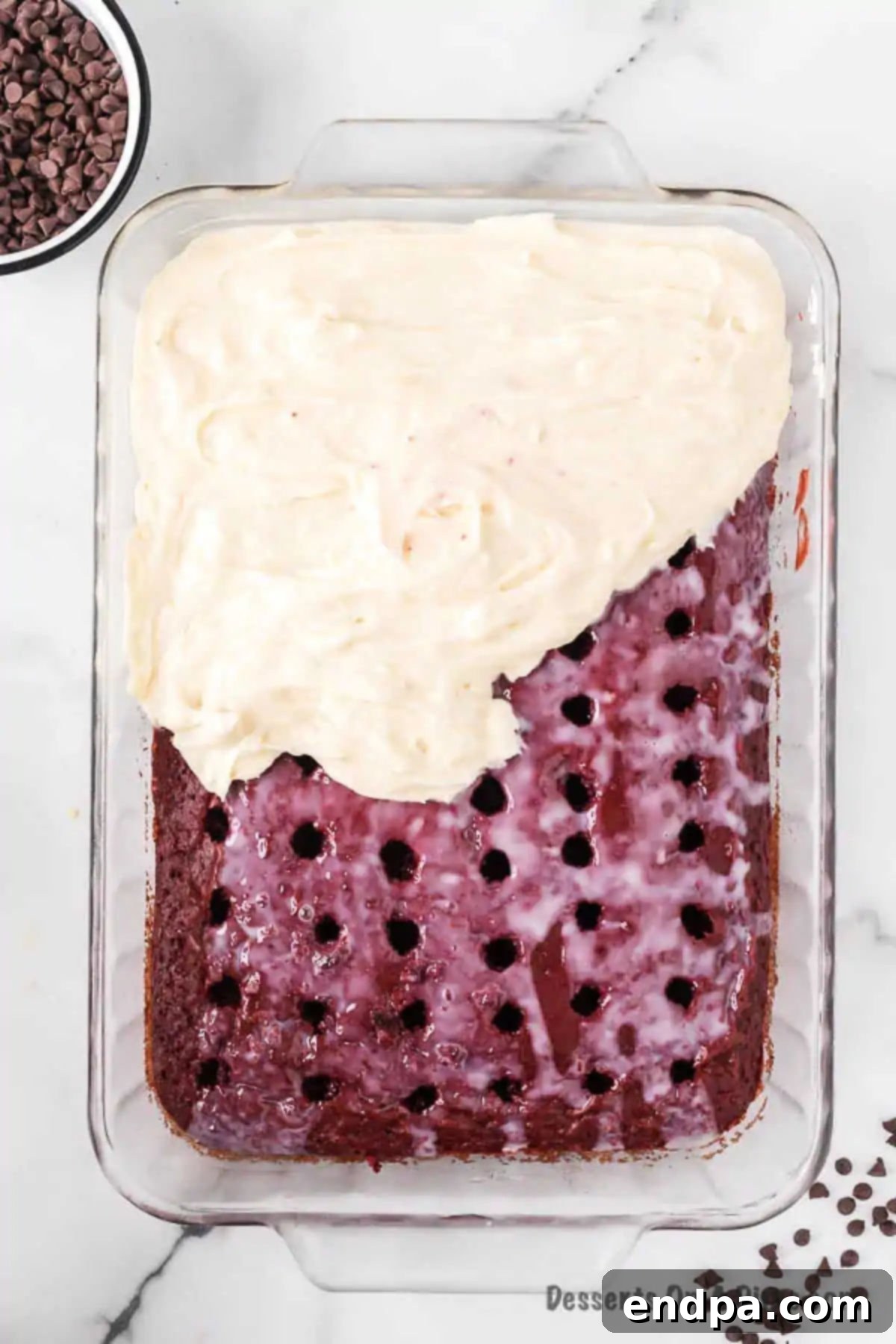 Red Velvet Infusion Cake 8 Cream cheese frosting being spread smoothly over the chilled Red Velvet Poke Cake.