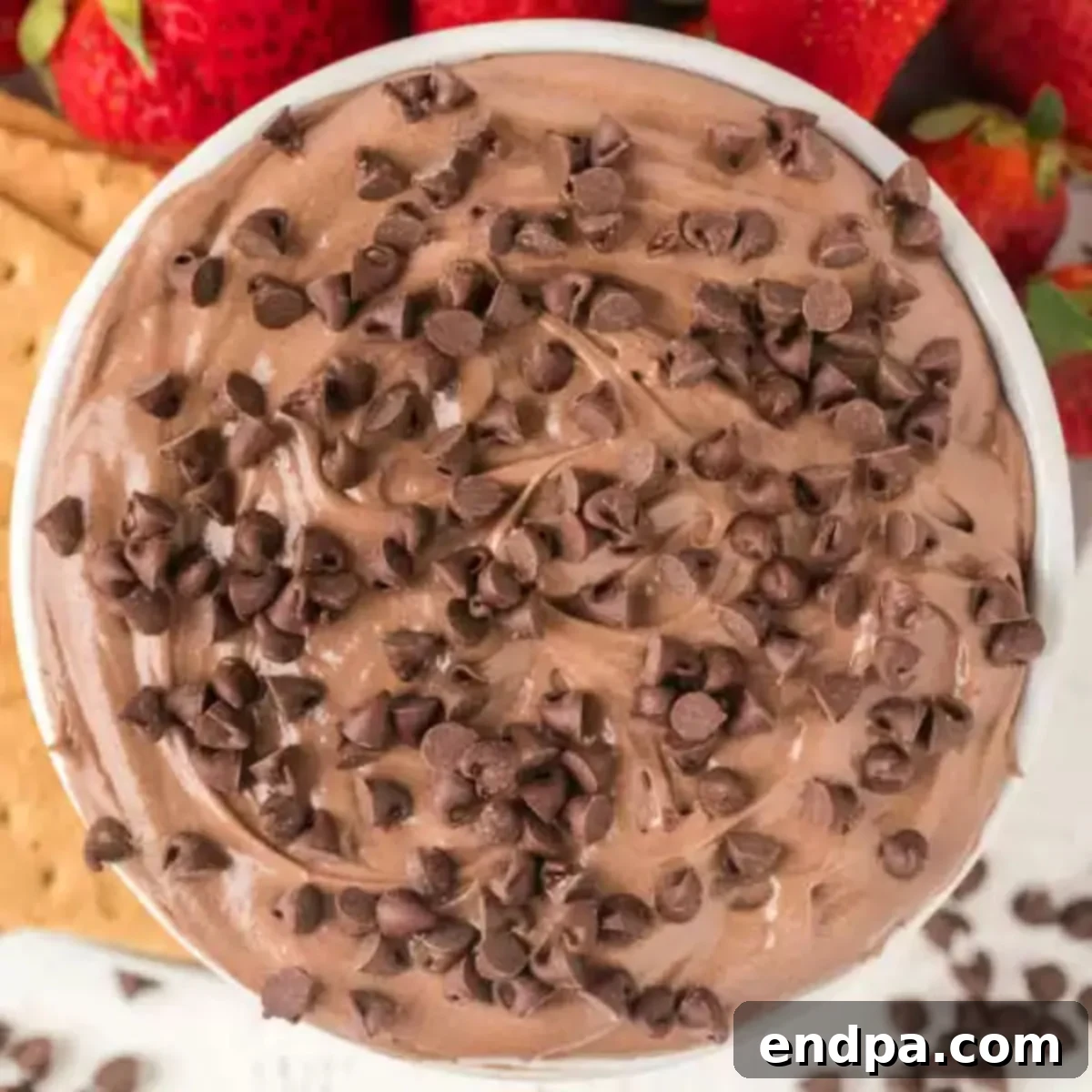 Decadent Brownie Dip 9 Close-up of a serving bowl filled with irresistible brownie batter dip, adorned with chocolate chips and ready for indulgence.