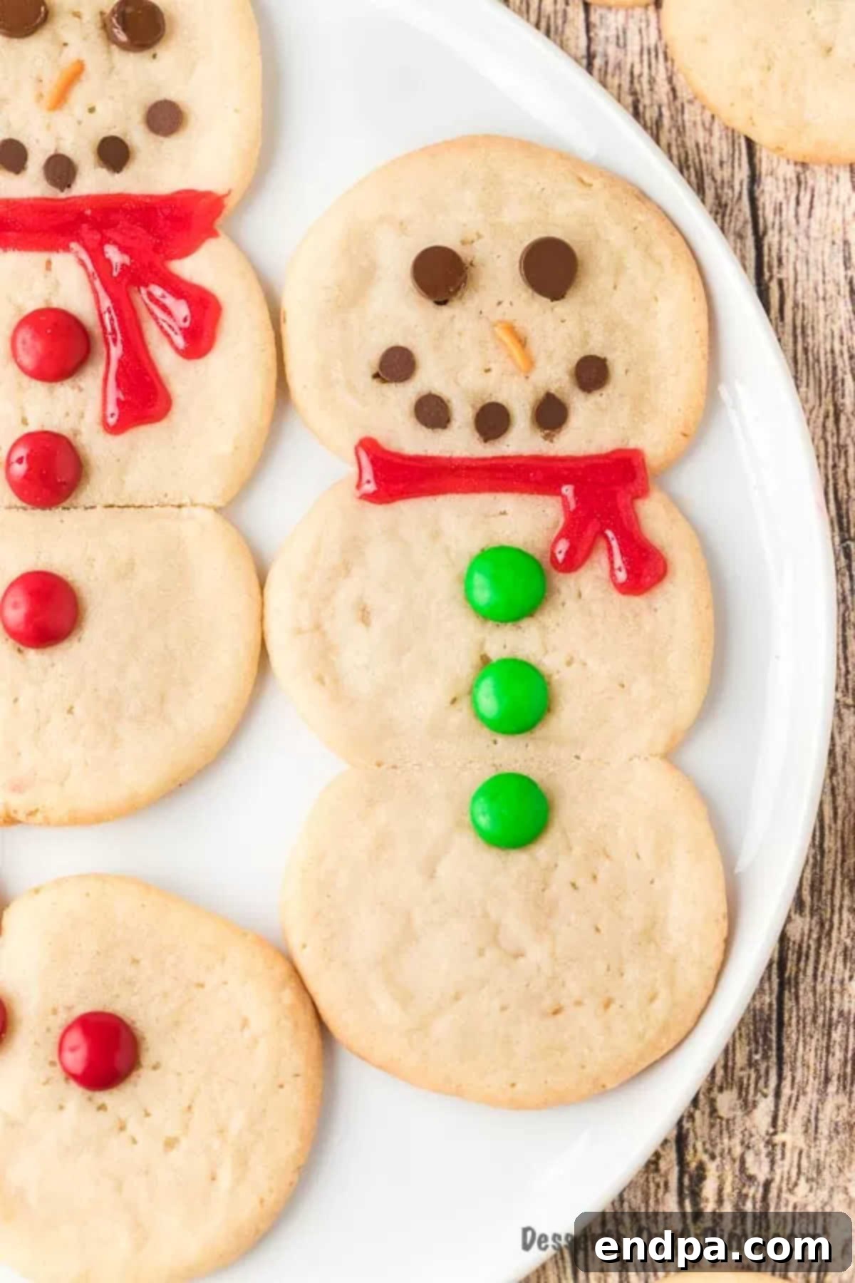 Whip Up Adorable Snowman Cookies 2 Smiling snowman cookies arranged on a baking sheet lined with wax paper, ready for holiday festivities.