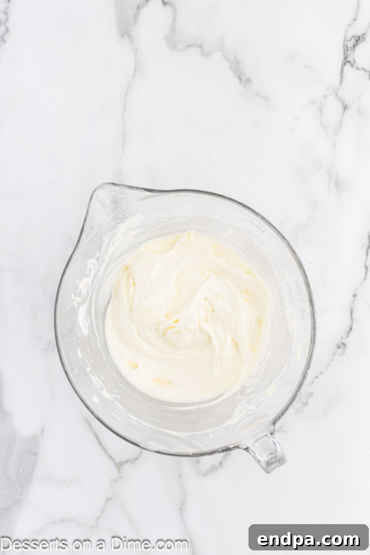 The cream cheese and butter mixture, combined with vanilla extract and powdered sugar, being mixed until smooth and creamy for the frosting.