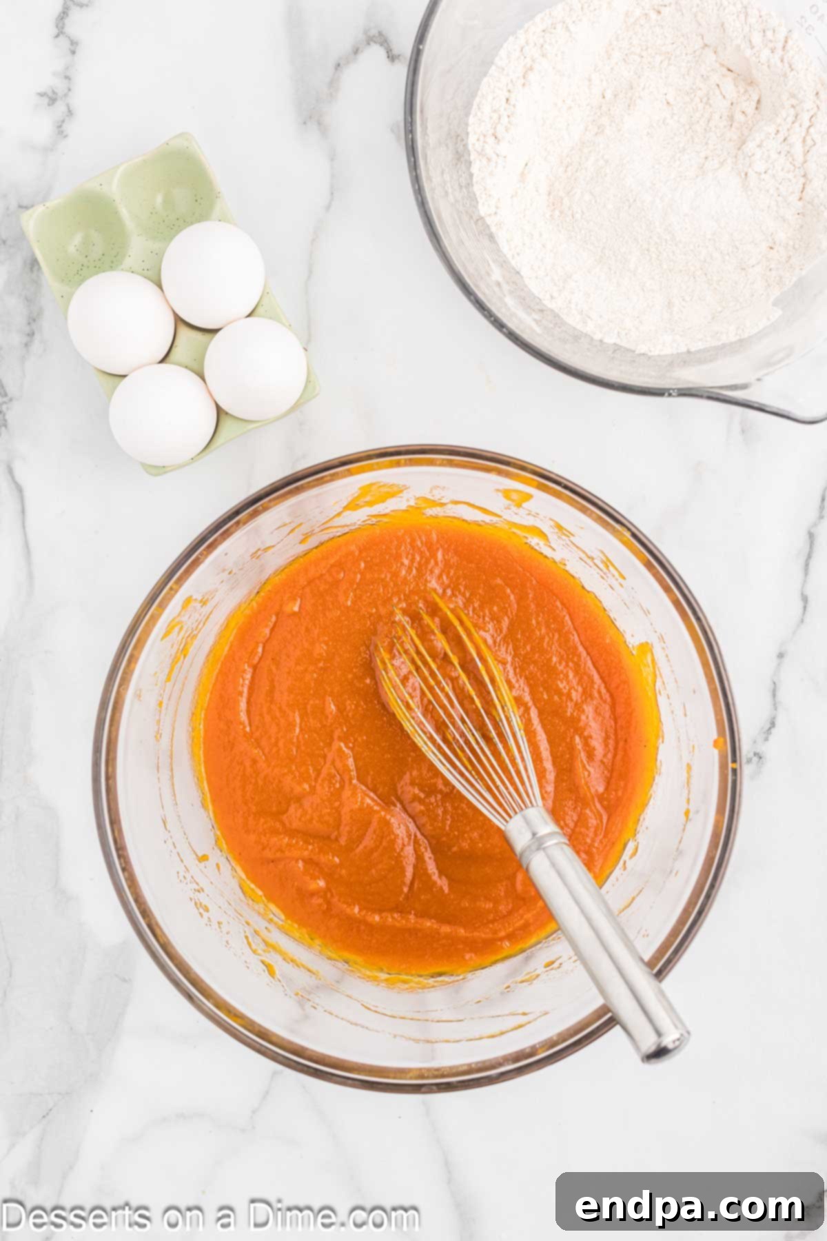 A separate mixing bowl containing the wet ingredients for pumpkin bars: granulated sugar, vegetable oil, and pure pumpkin puree, perfectly combined.