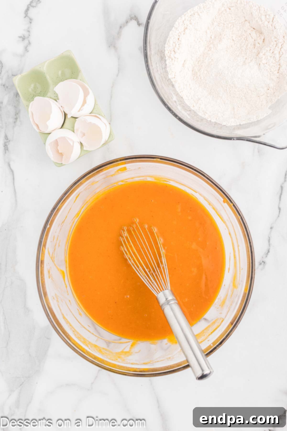 Large eggs being added to the pumpkin, sugar, and oil mixture in a bowl, ready to be whisked.
