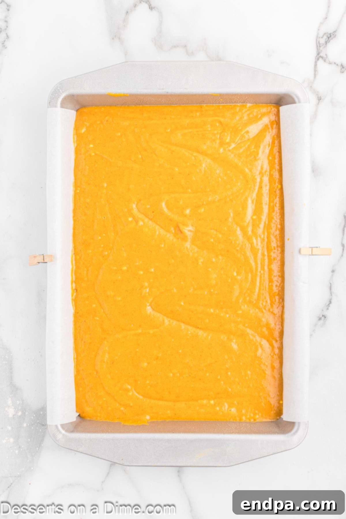 Smooth pumpkin bar batter evenly spread into the prepared 9x13 inch baking dish, ready for the oven.