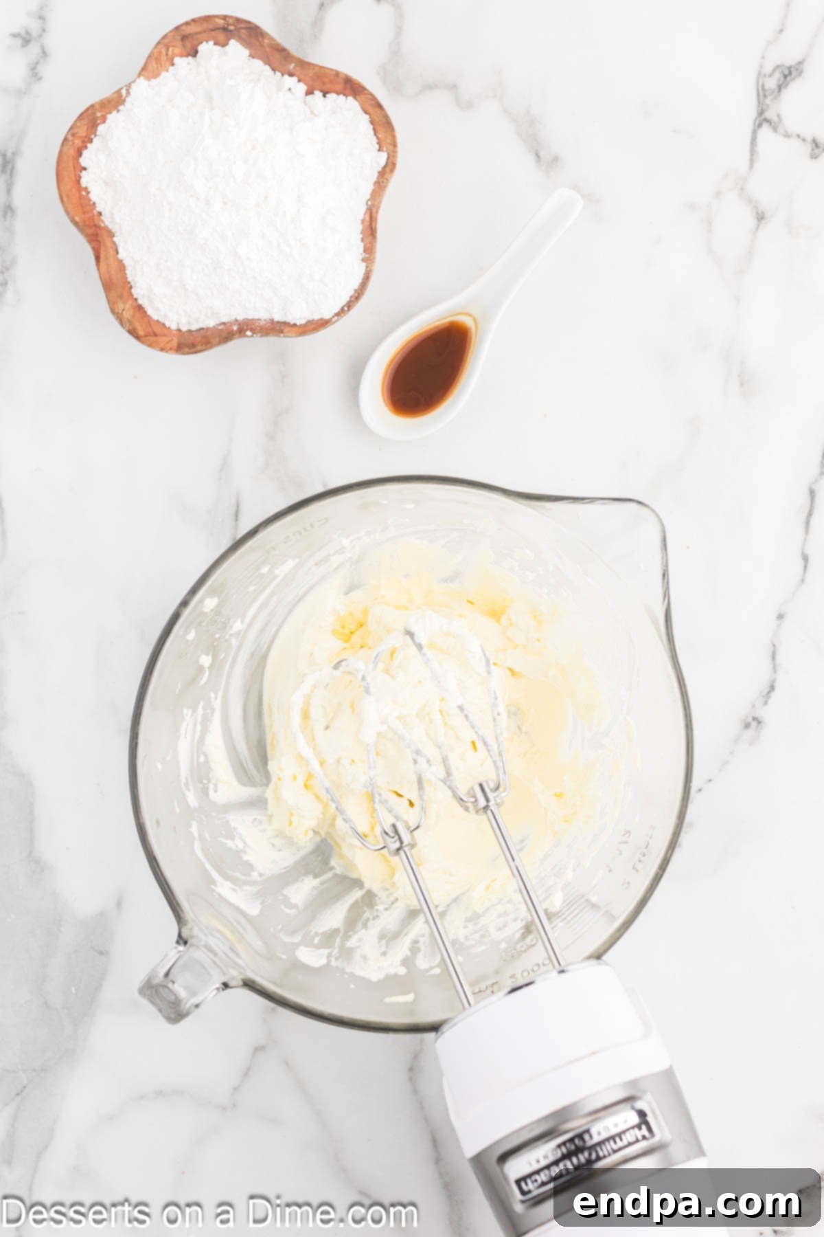 Softened cream cheese and butter being beaten together in a mixing bowl until light and fluffy, forming the base of the frosting.