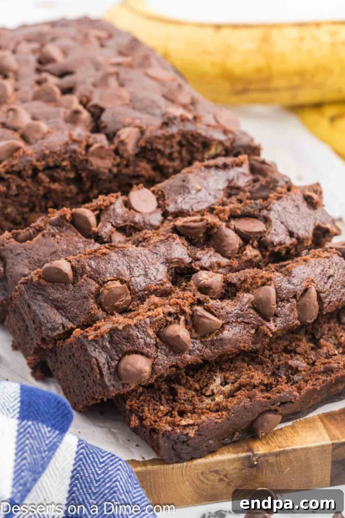 Ultimate Chocolate Banana Loaf 2 Slices of moist Chocolate Banana Bread with visible chocolate chips on a wooden board.