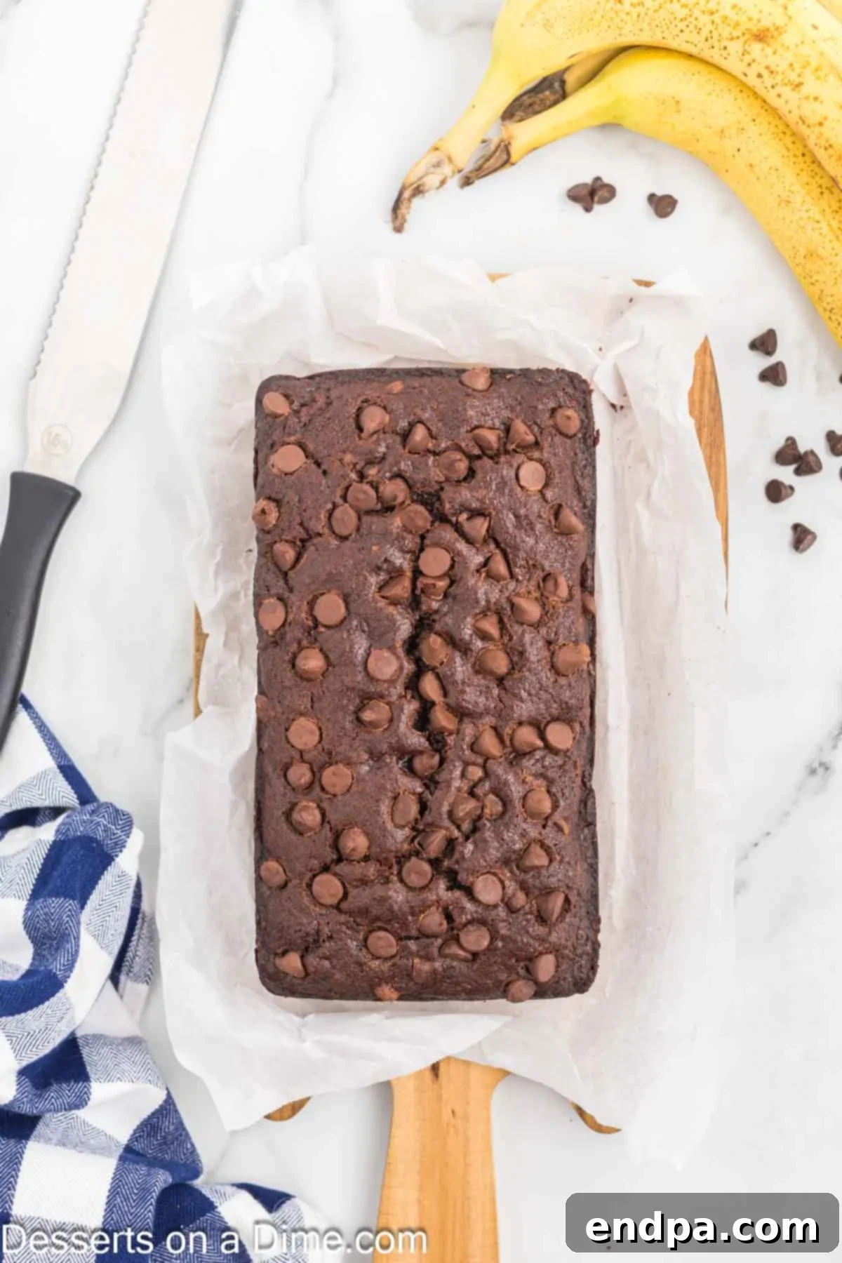 Ultimate Chocolate Banana Loaf 12 A baked loaf of Chocolate Banana Bread resting on parchment paper on a wire rack.