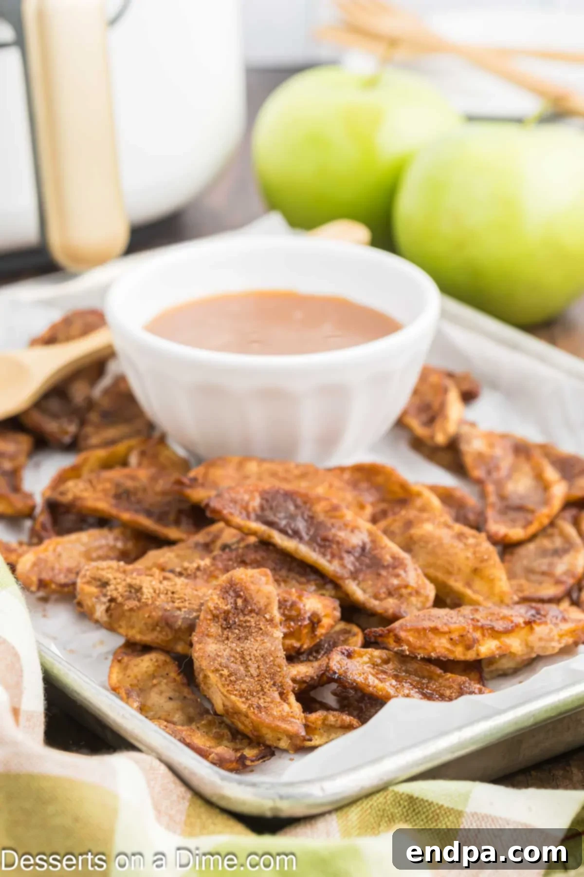 Platter of air fryer apple slices with a bowl of caramel for dipping. 