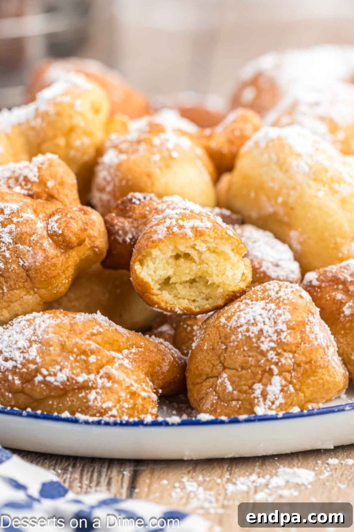 A plate brimming with golden brown funnel cake bites, generously dusted with white powdered sugar, ready to be enjoyed.