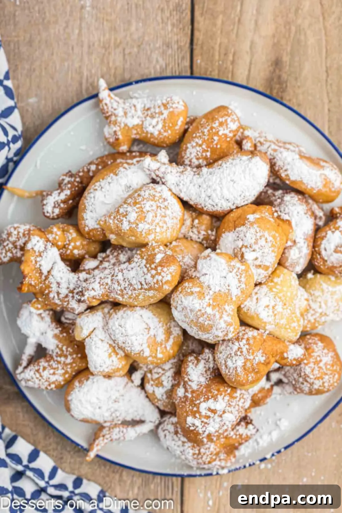 A plate of golden funnel cake bites generously covered with powdered sugar, creating a delicious and inviting dessert display.