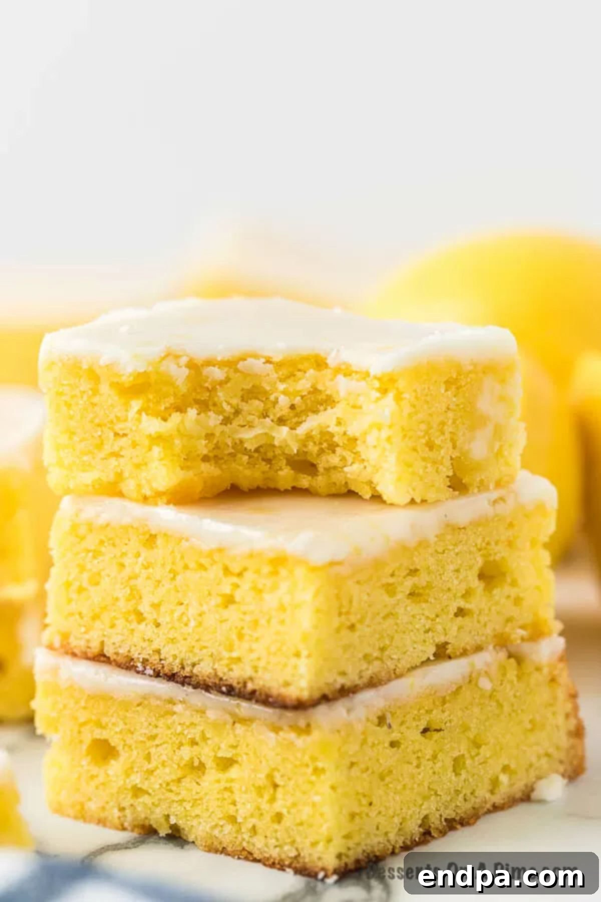 Lemon Brownies stacked together on a white plate, garnished with lemon zest.