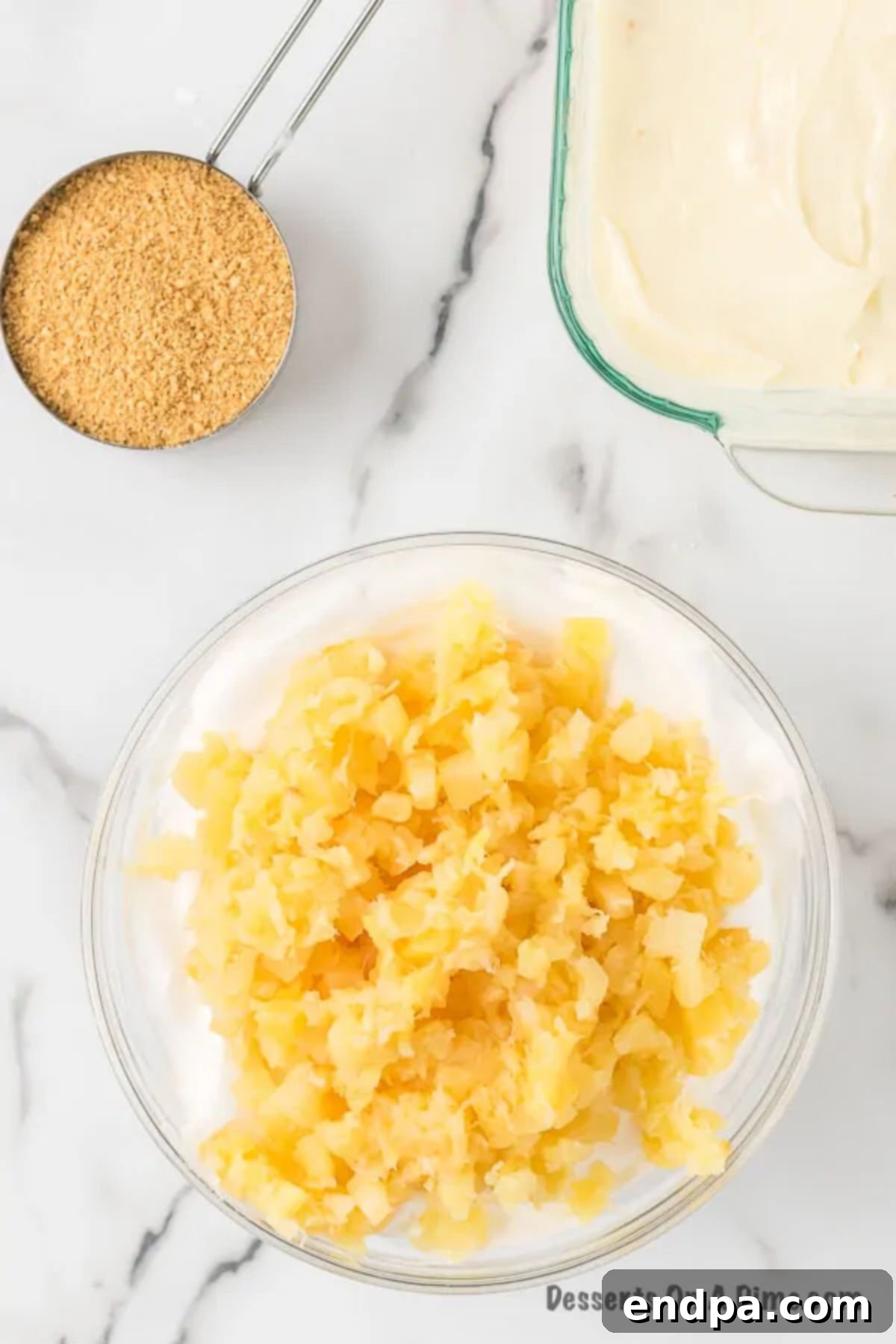 A large bowl containing the cream cheese mixture, with thoroughly drained crushed pineapple gently folded in by hand using a spatula.