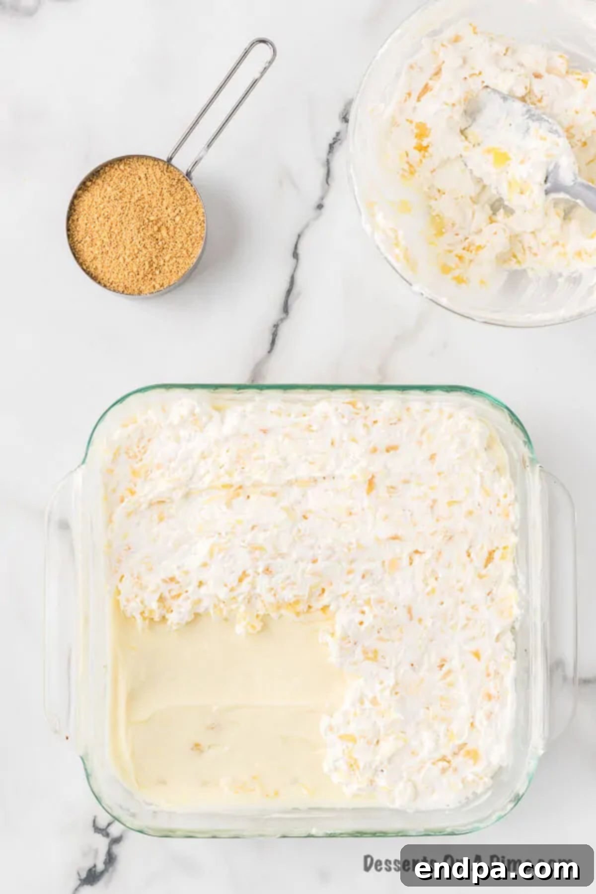 The creamy pineapple-cream cheese mixture evenly spread over the cooled graham cracker crust in a baking dish.