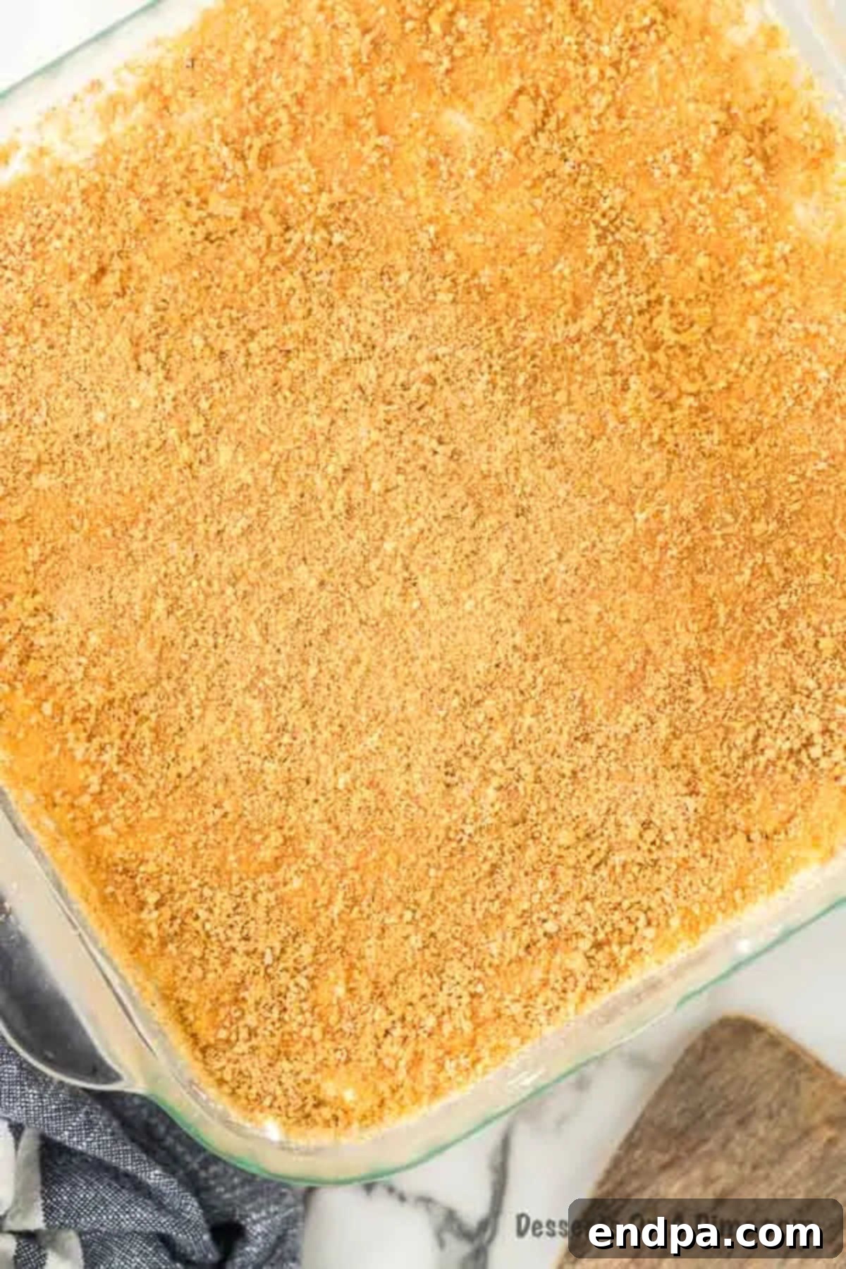 The top layer of whipped cream and pineapple spread over the cream cheese layer, with a final sprinkle of graham cracker crumbs.