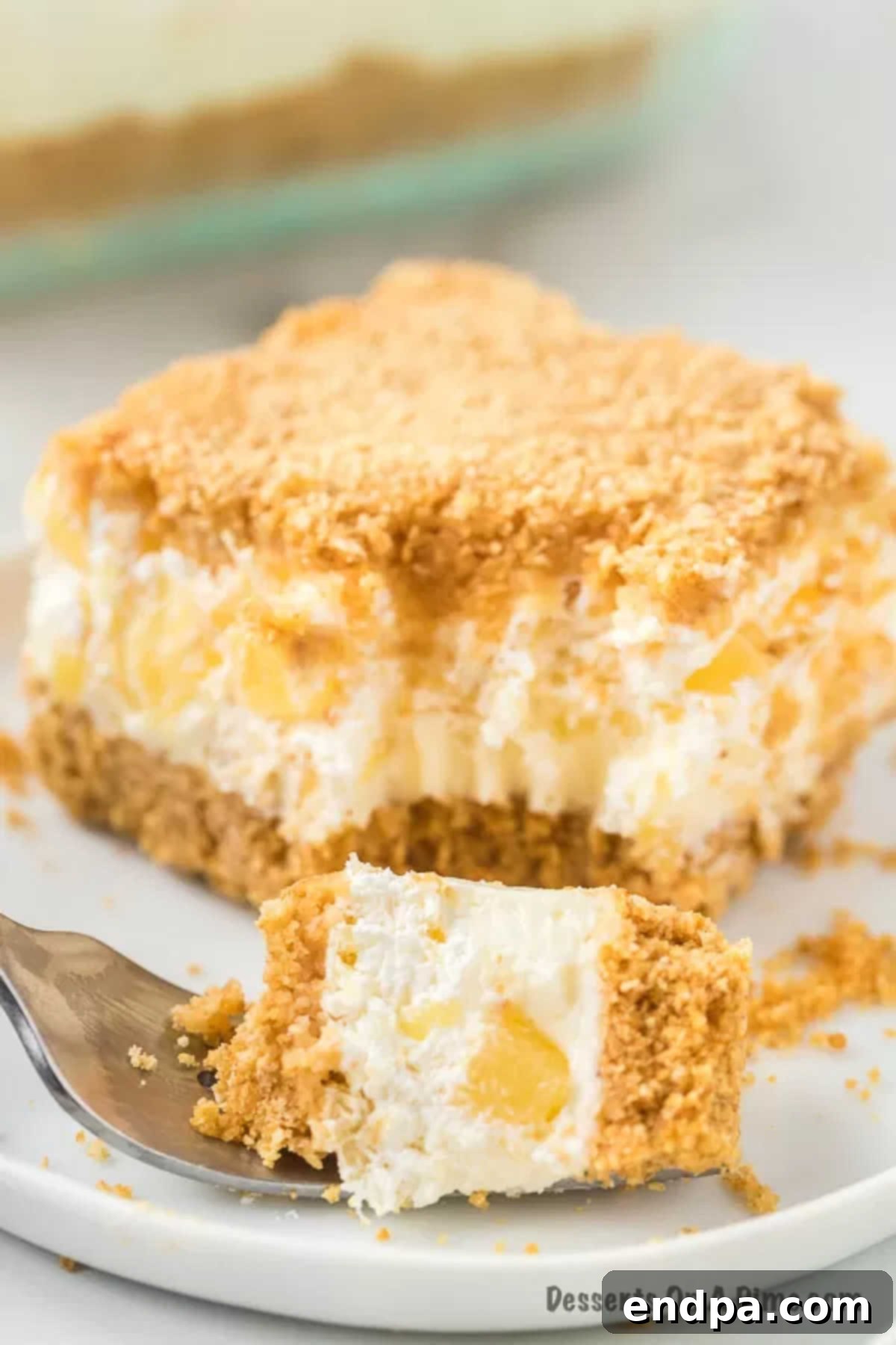 A beautifully presented slice of Pineapple Dream Dessert on a white plate, showcasing all its distinct layers.