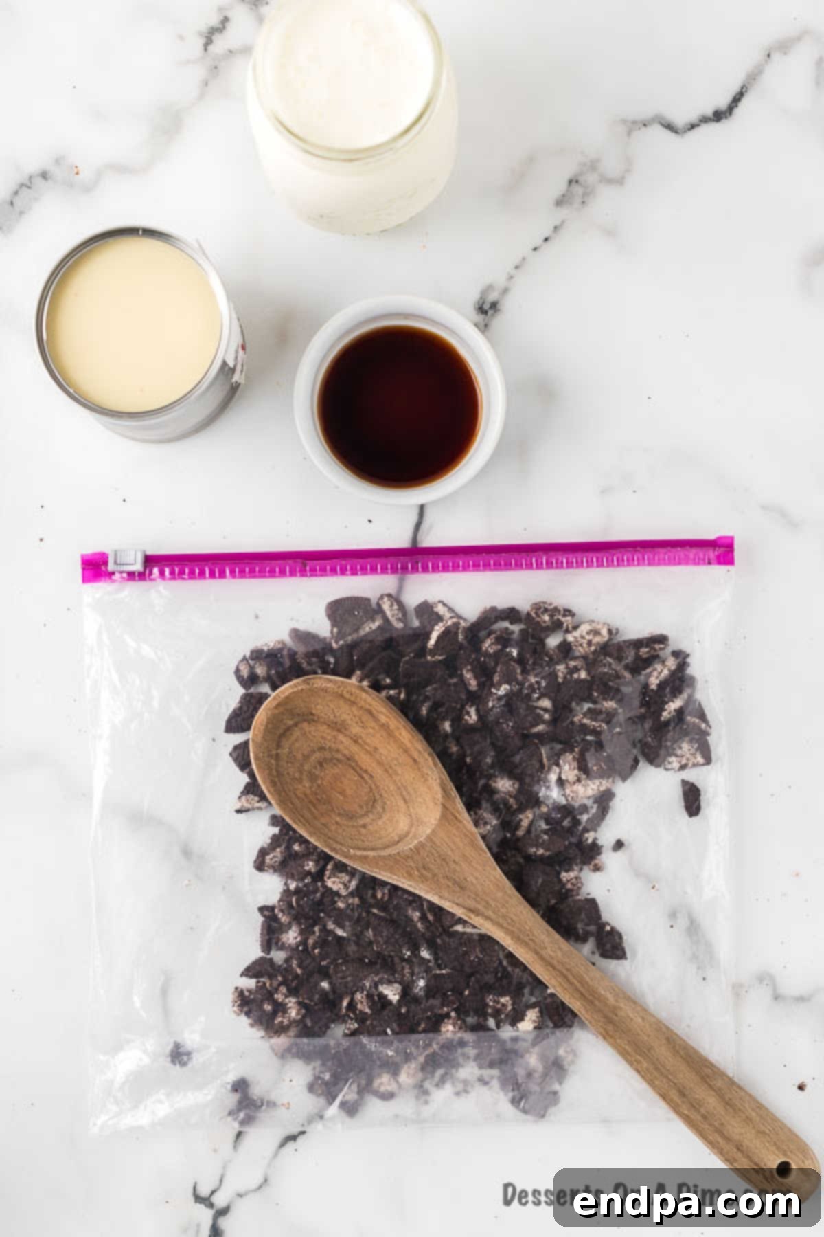 Midnight Cookie Swirl Ice Cream 4 Ziploc bag with Oreo cookies being crushed with a wooden spoon.