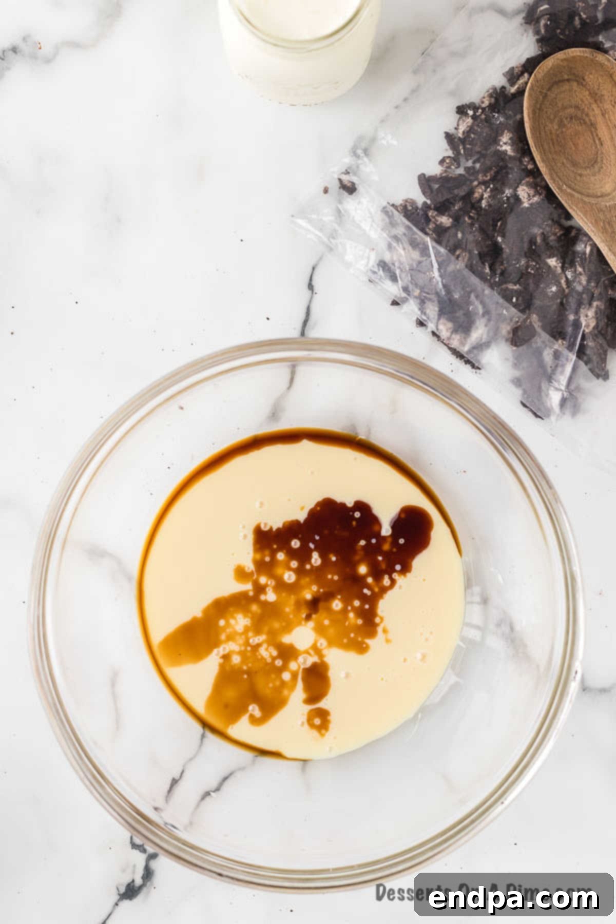 Midnight Cookie Swirl Ice Cream 5 Mixing bowl with sweetened condensed milk and vanilla extract being stirred together.