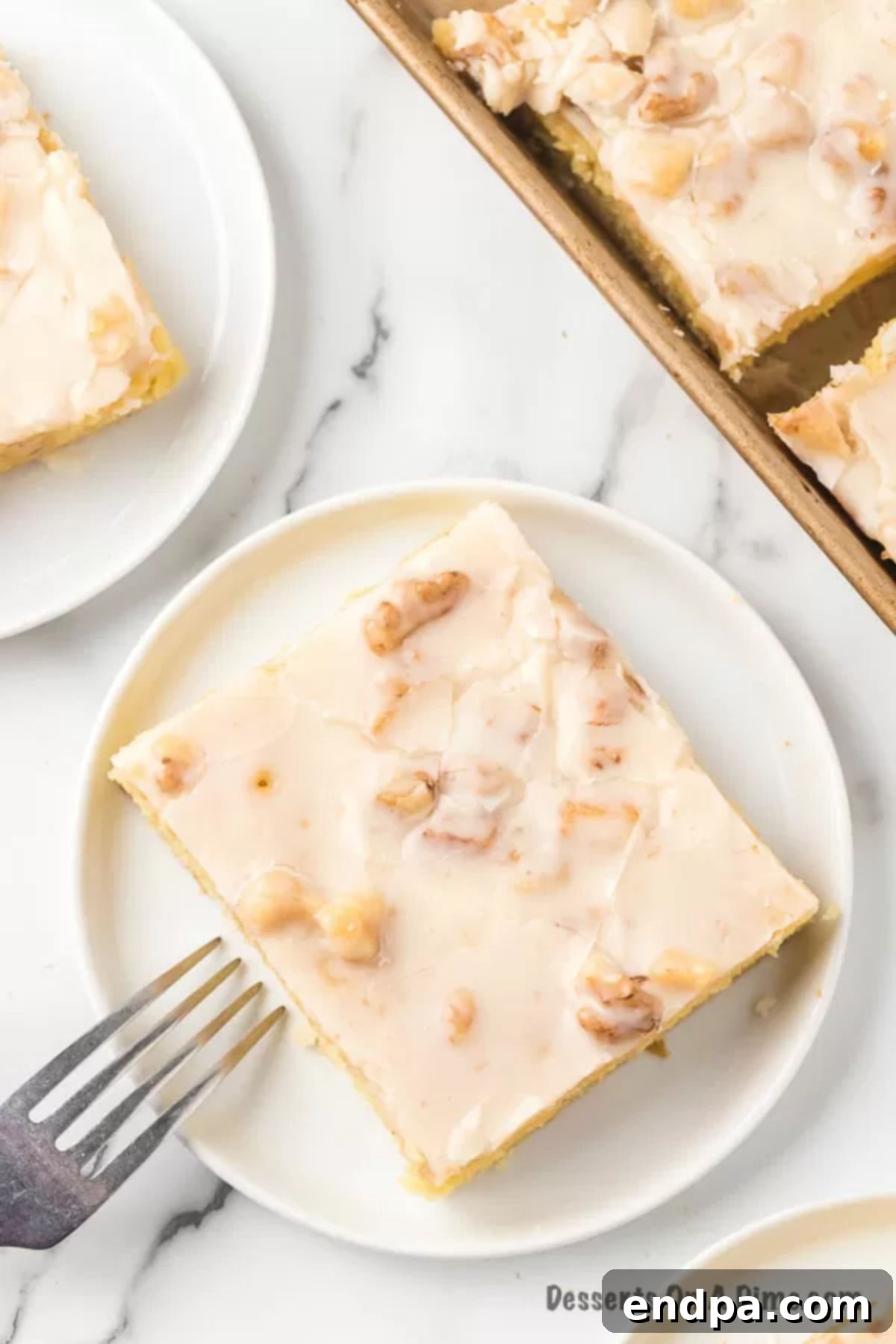 A perfectly sliced piece of moist White Texas Sheet Cake with rich, decadent white frosting on a plate.