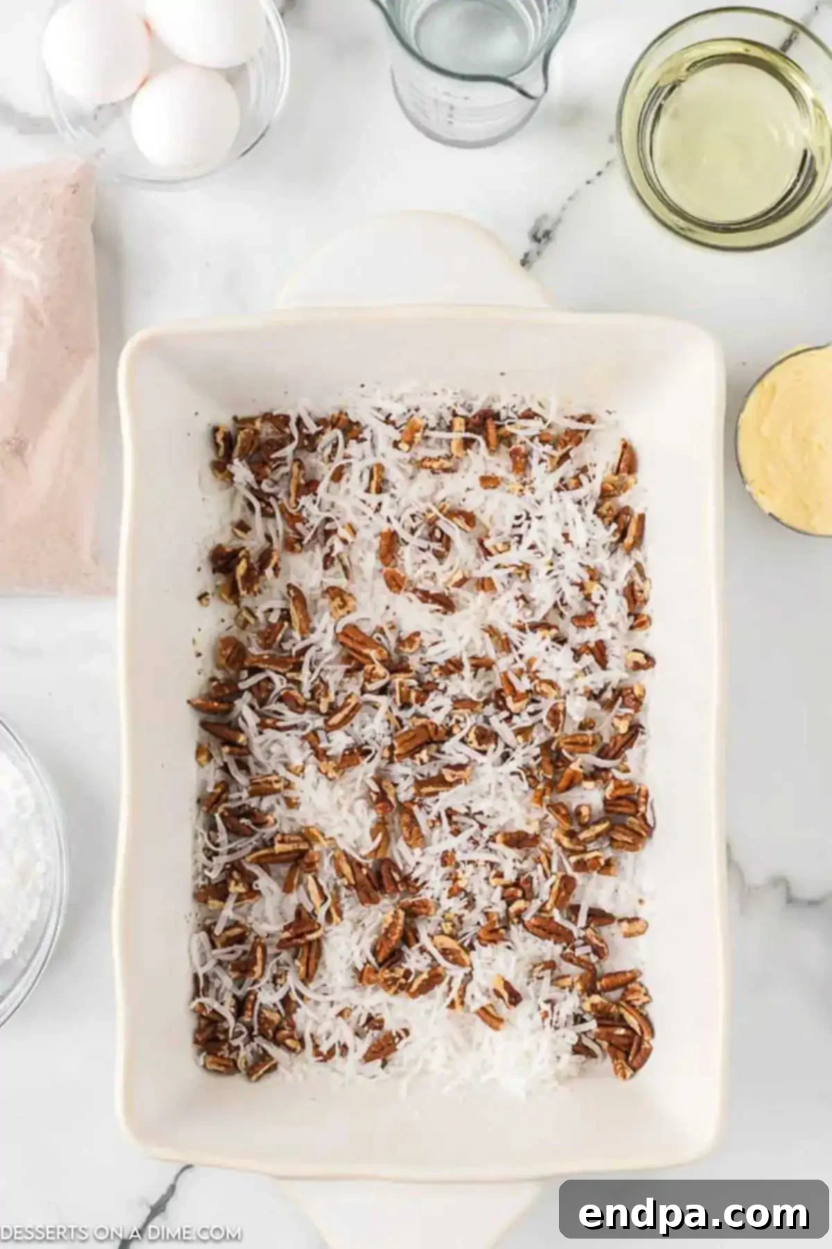 Decadent German Chocolate Cheesecake Bars 3 Pecans and coconut in bottom of baking dish.