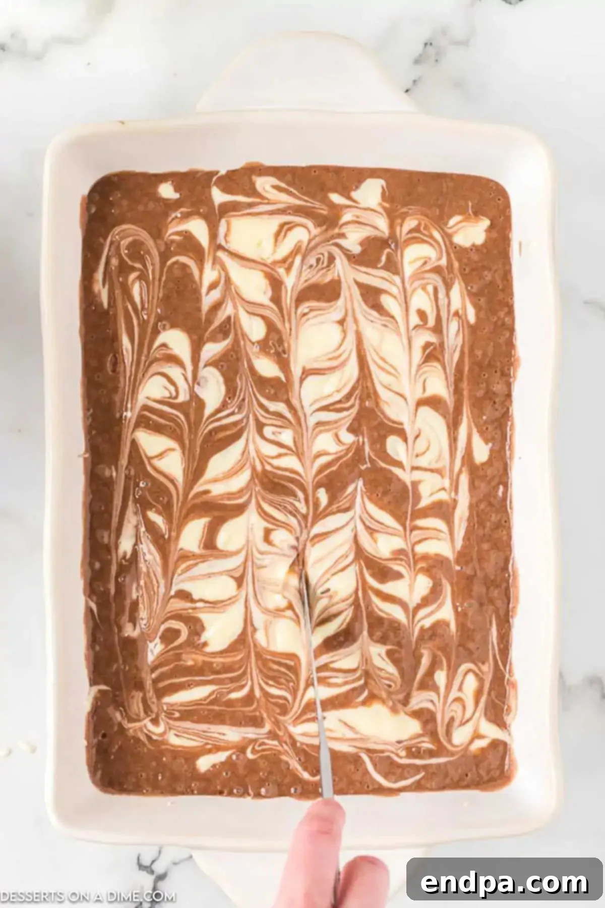 Decadent German Chocolate Cheesecake Bars 8 Mixture swirled in pan with a knife.