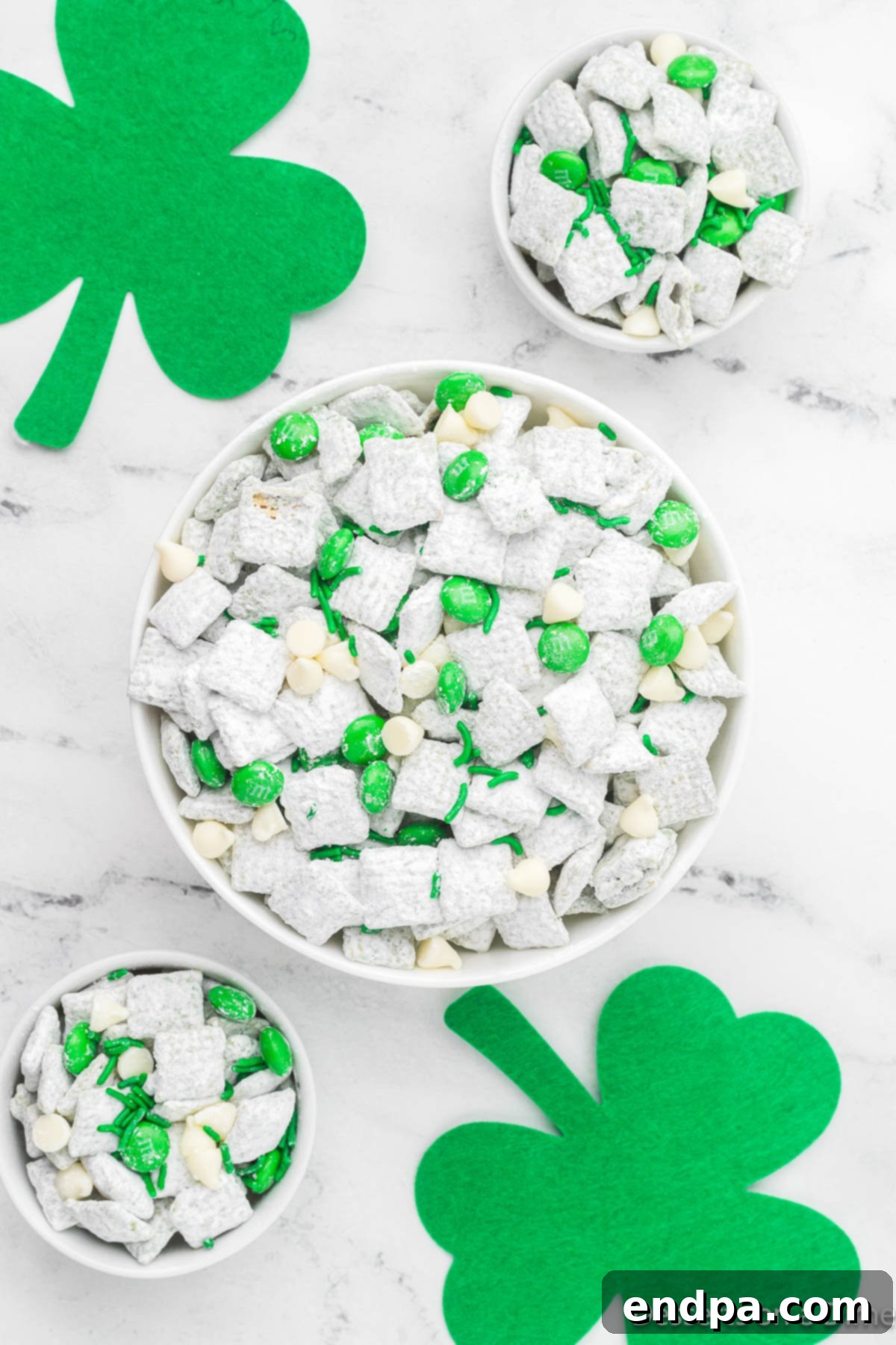 A large bowl filled with vibrant green St. Patrick's Day Puppy Chow, featuring Chex cereal coated in green candy melts, powdered sugar, and green sprinkles, ready to be enjoyed.