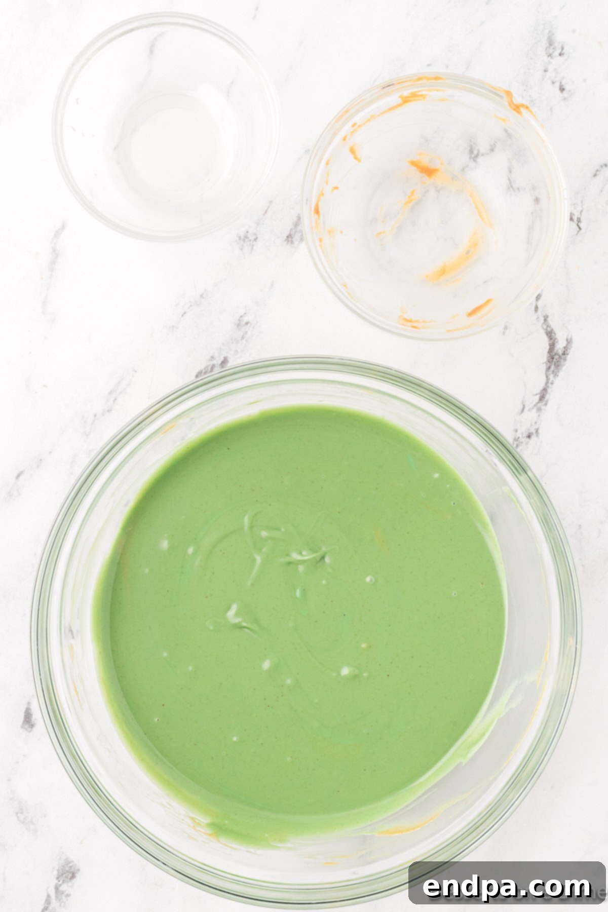 Close-up of the melted and smoothly combined green candy melts and peanut butter mixture in a bowl, ready to be poured over cereal.