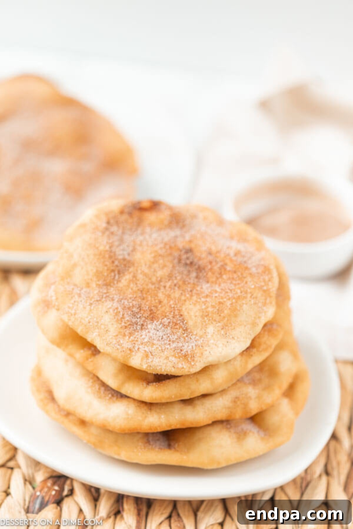 Golden Crispy Elephant Ears Delight 2 Four golden-brown elephant ears stacked on a white serving plate, glistening with a generous coating of cinnamon sugar.