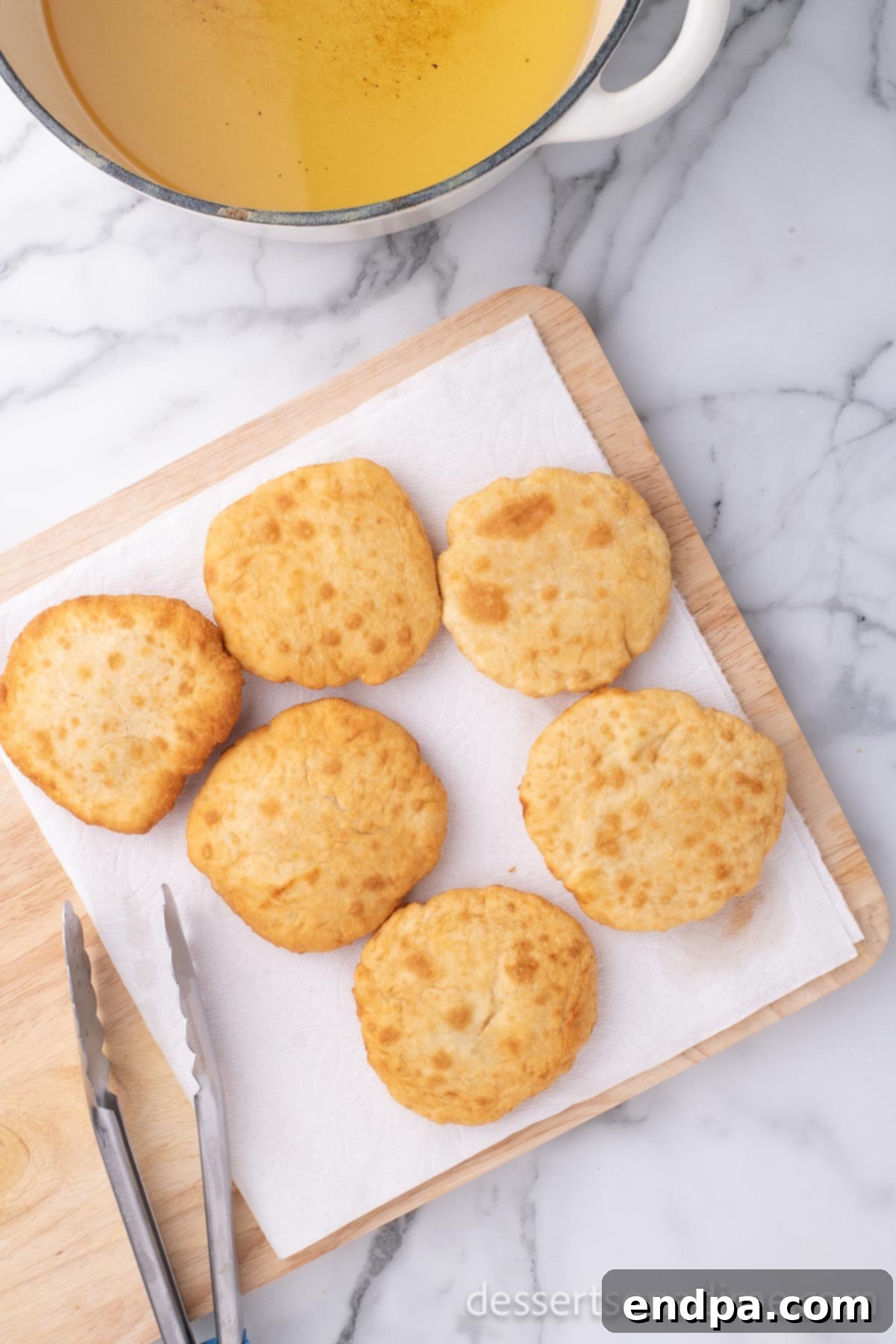 Golden Crispy Elephant Ears Delight 11 Fried elephant ears are transferred onto a plate lined with paper towels to absorb excess oil.