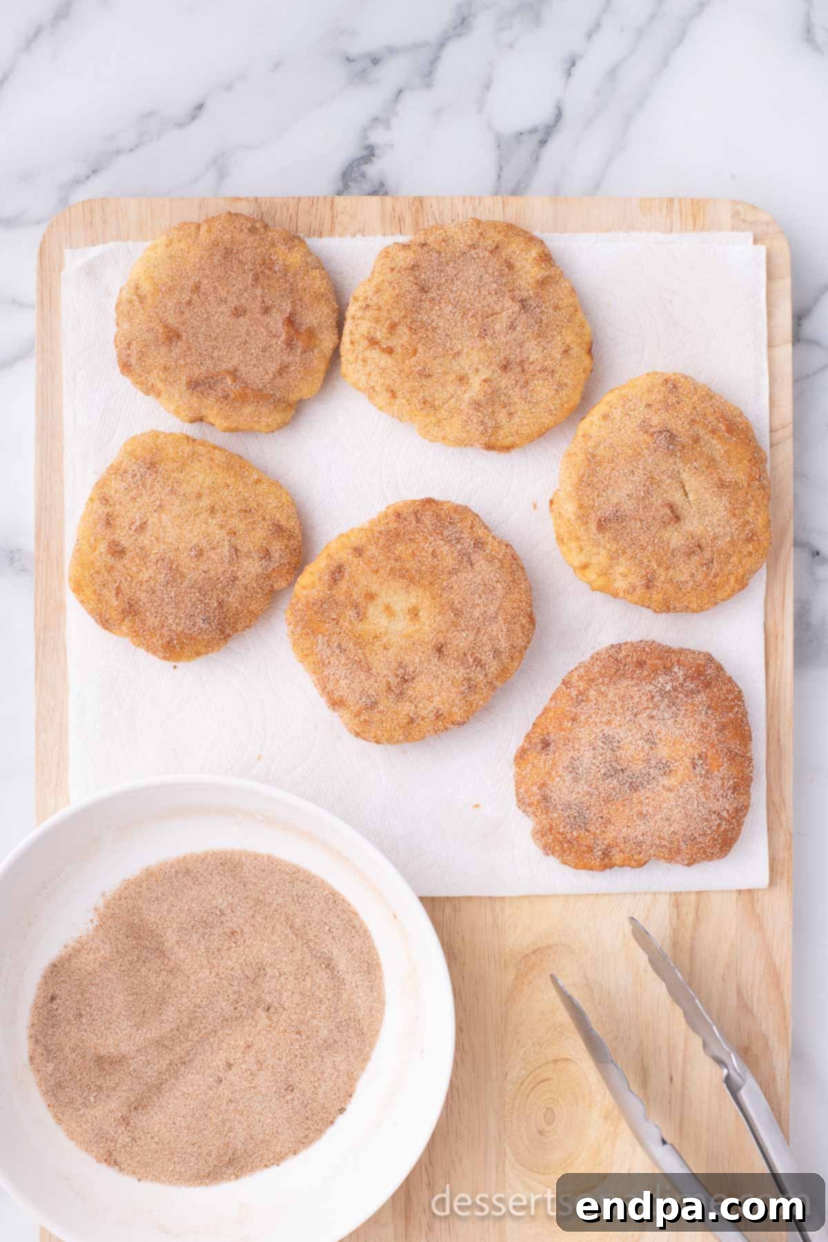 Golden Crispy Elephant Ears Delight 13 Warm, fried elephant ears, still resting on paper towels, are generously sprinkled with the prepared cinnamon sugar mixture.