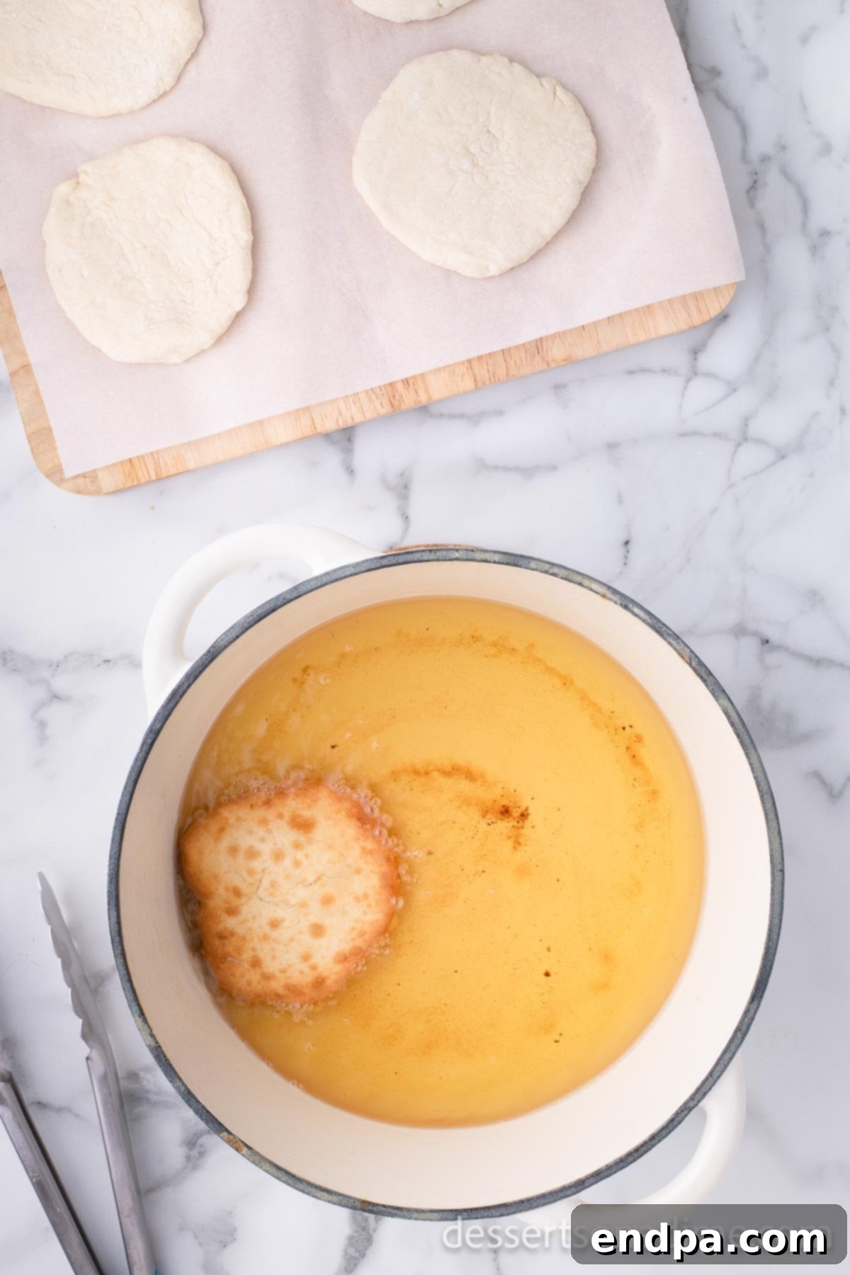 Golden Crispy Elephant Ears Delight 10 A round disc of dough is carefully placed into the hot oil, sizzling and beginning to puff up as it fries.