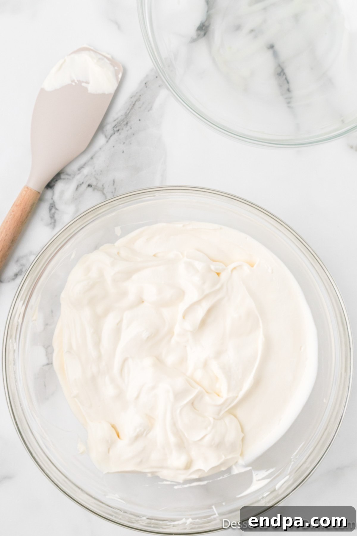 Mixing bowl with heavy whipping cream forming peaks. 