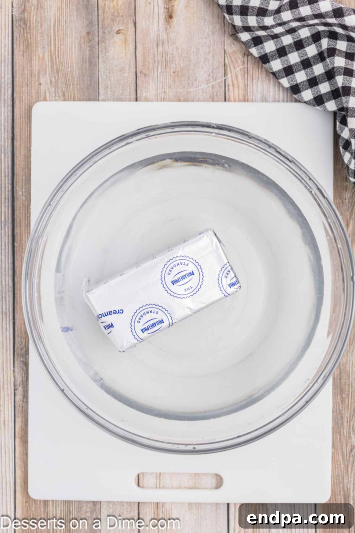 Effortless Ways to Soften Cream Cheese 3 Block of cream cheese in wrapper placed in a bowl, ready for a water bath.