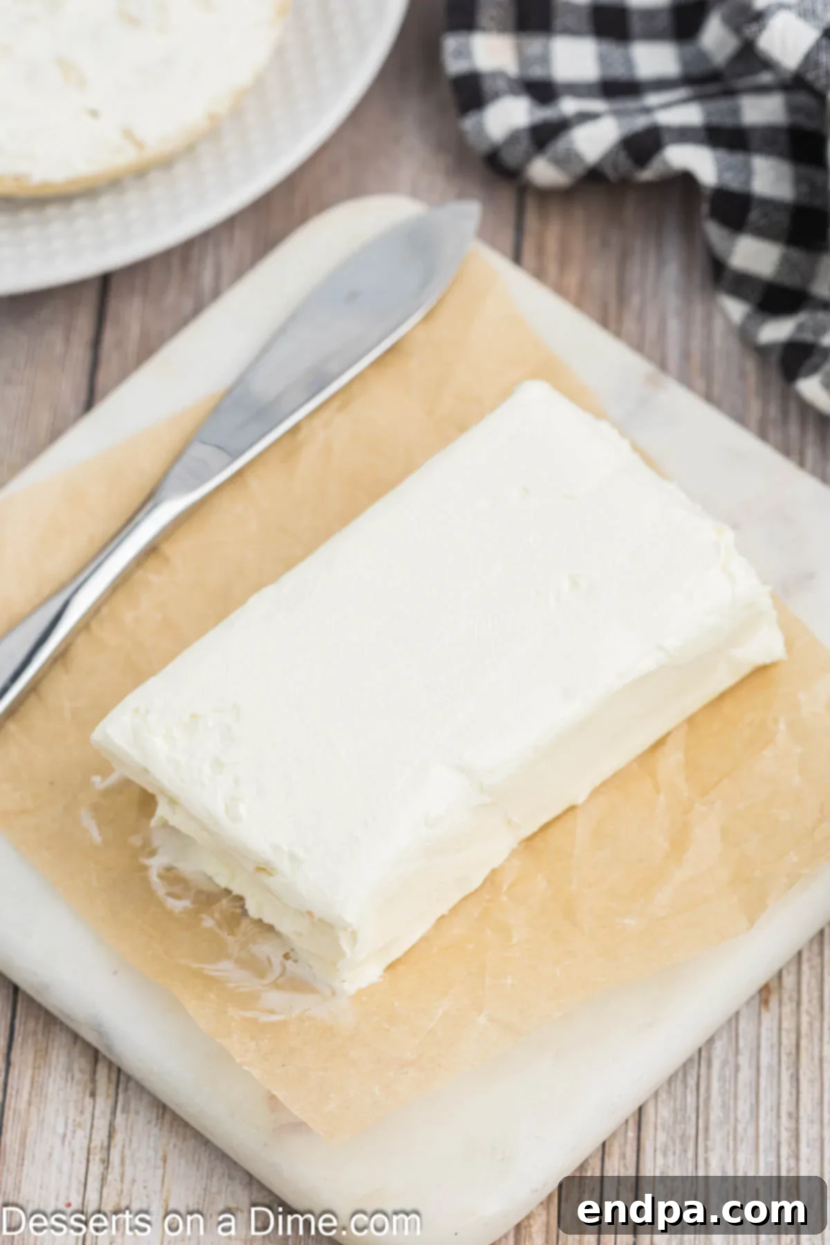 Effortless Ways to Soften Cream Cheese 4 Cream cheese unwrapped on a cutting board, ready to be diced.