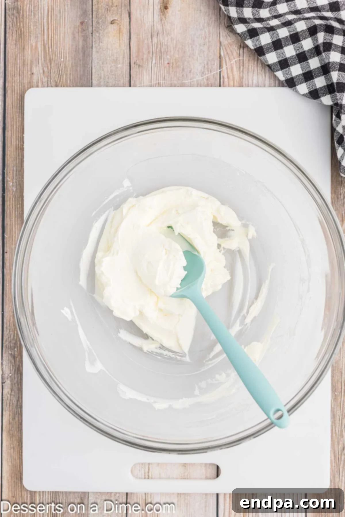 Effortless Ways to Soften Cream Cheese 7 Softened cream cheese in a bowl, being gently stirred with a spatula.