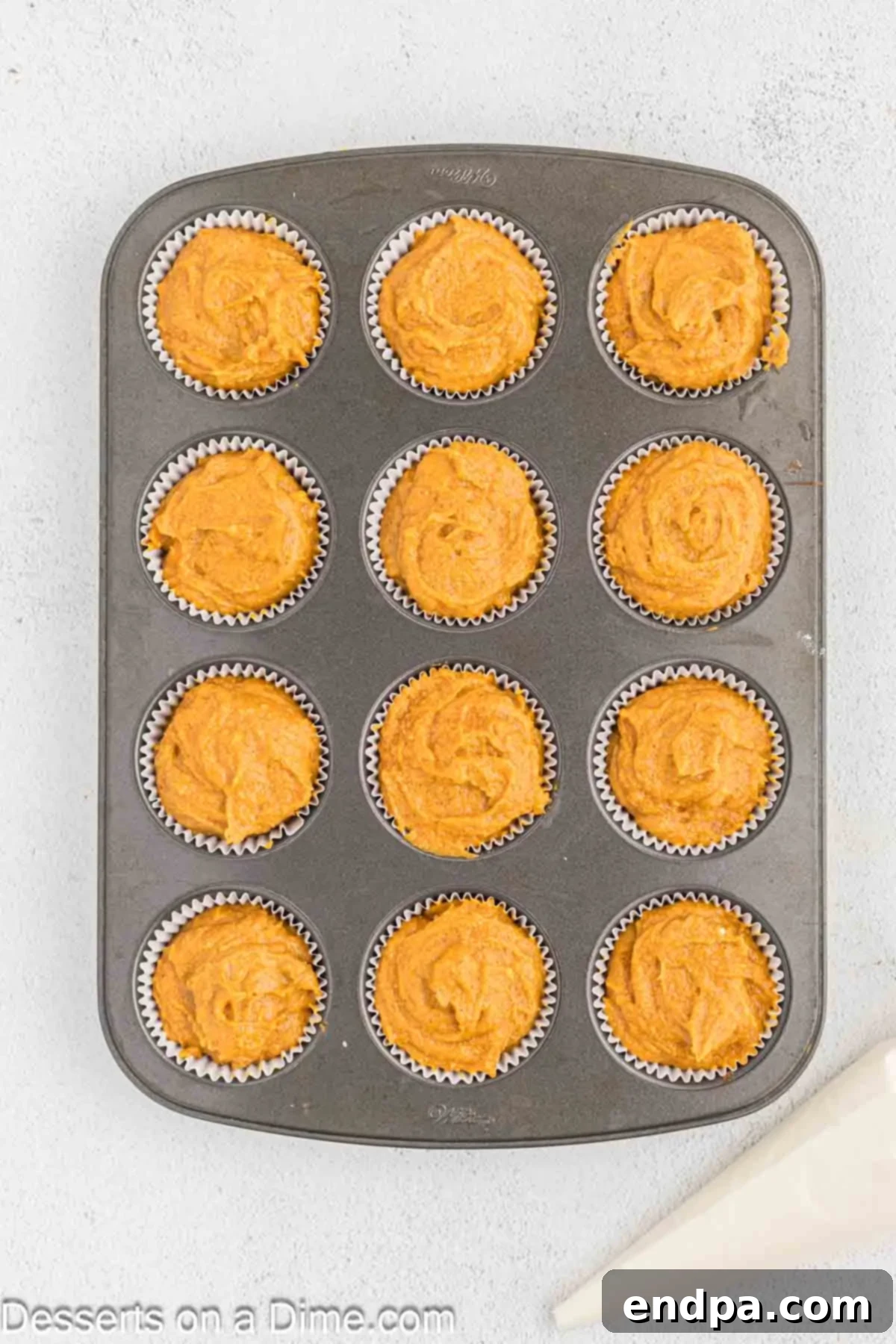 Starbucks-Style Pumpkin Spice Cream Cheese Muffins 10 Pumpkin muffin batter evenly divided into muffin liners in a 12-cup tin.