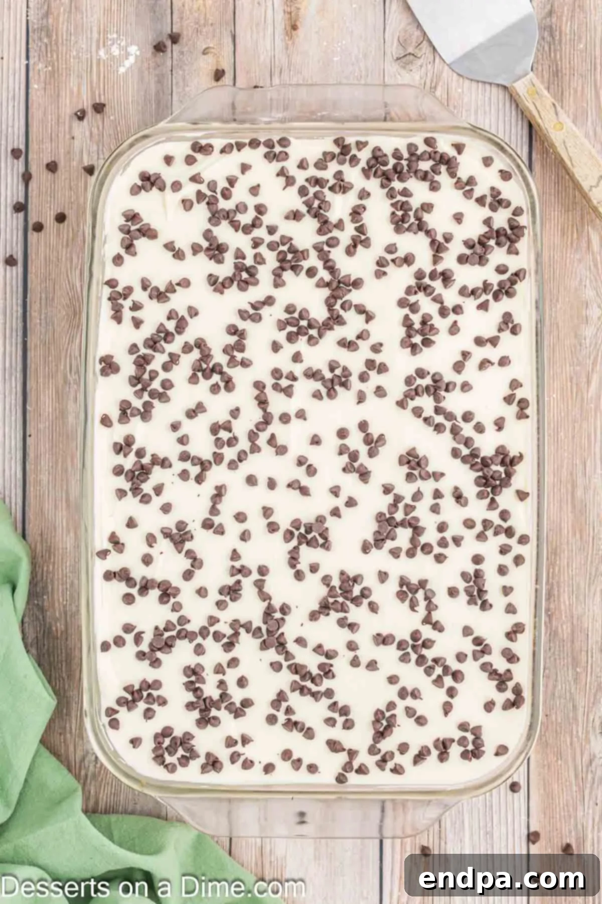 Frosting spread on cake and topped with chocolate chips.