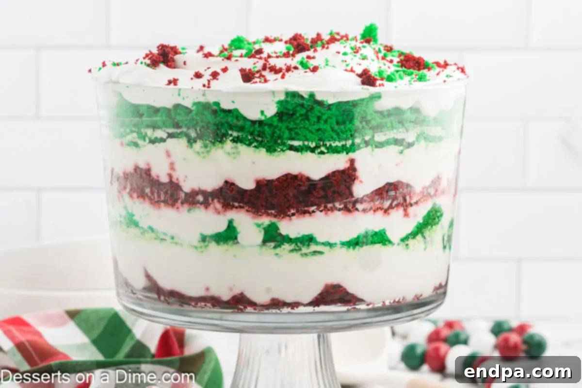Christmas trifle in a glass dish ready to serve, showcasing red and green layers with whipped cream on top.