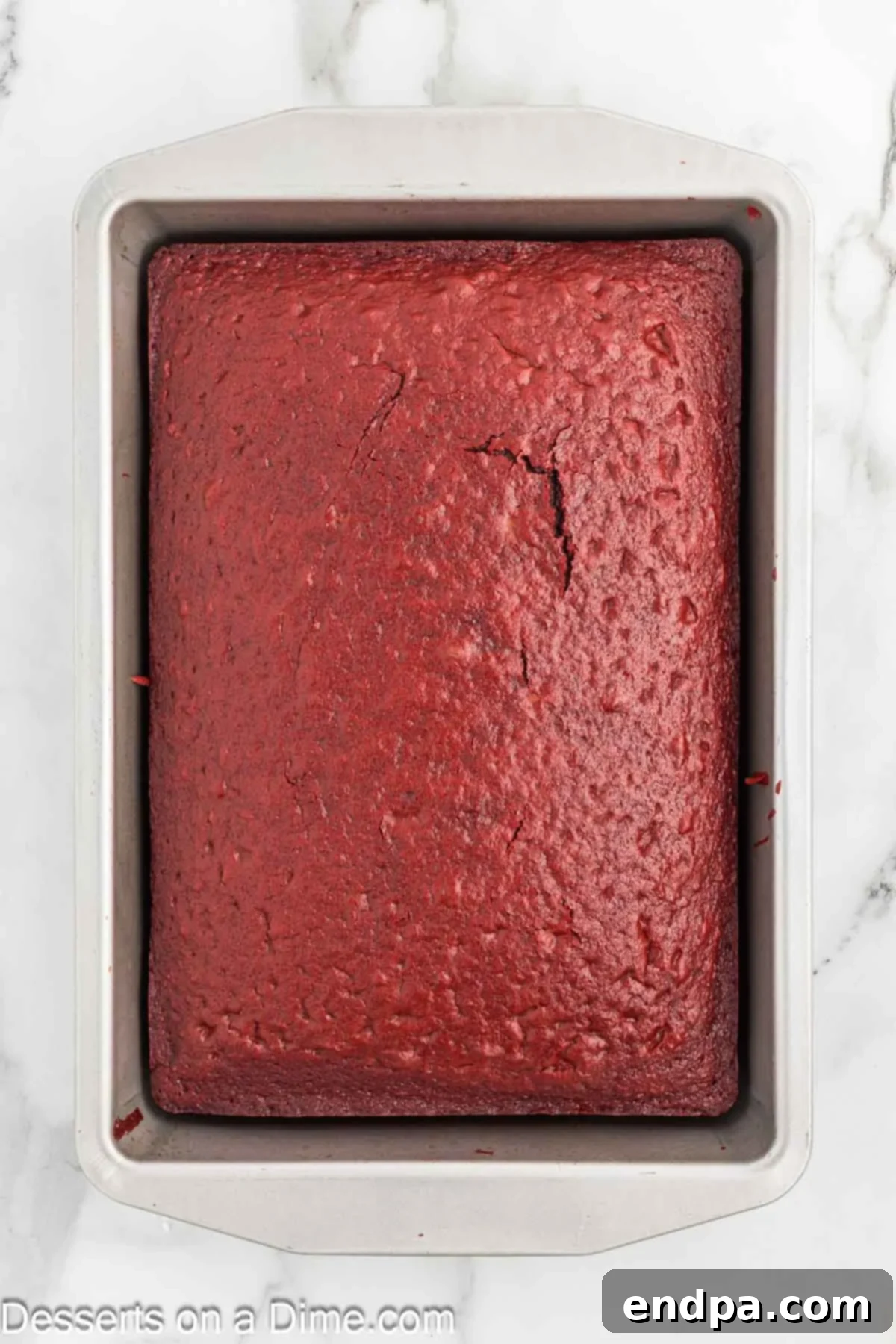 Red velvet cake cooling in baking dish after baking.