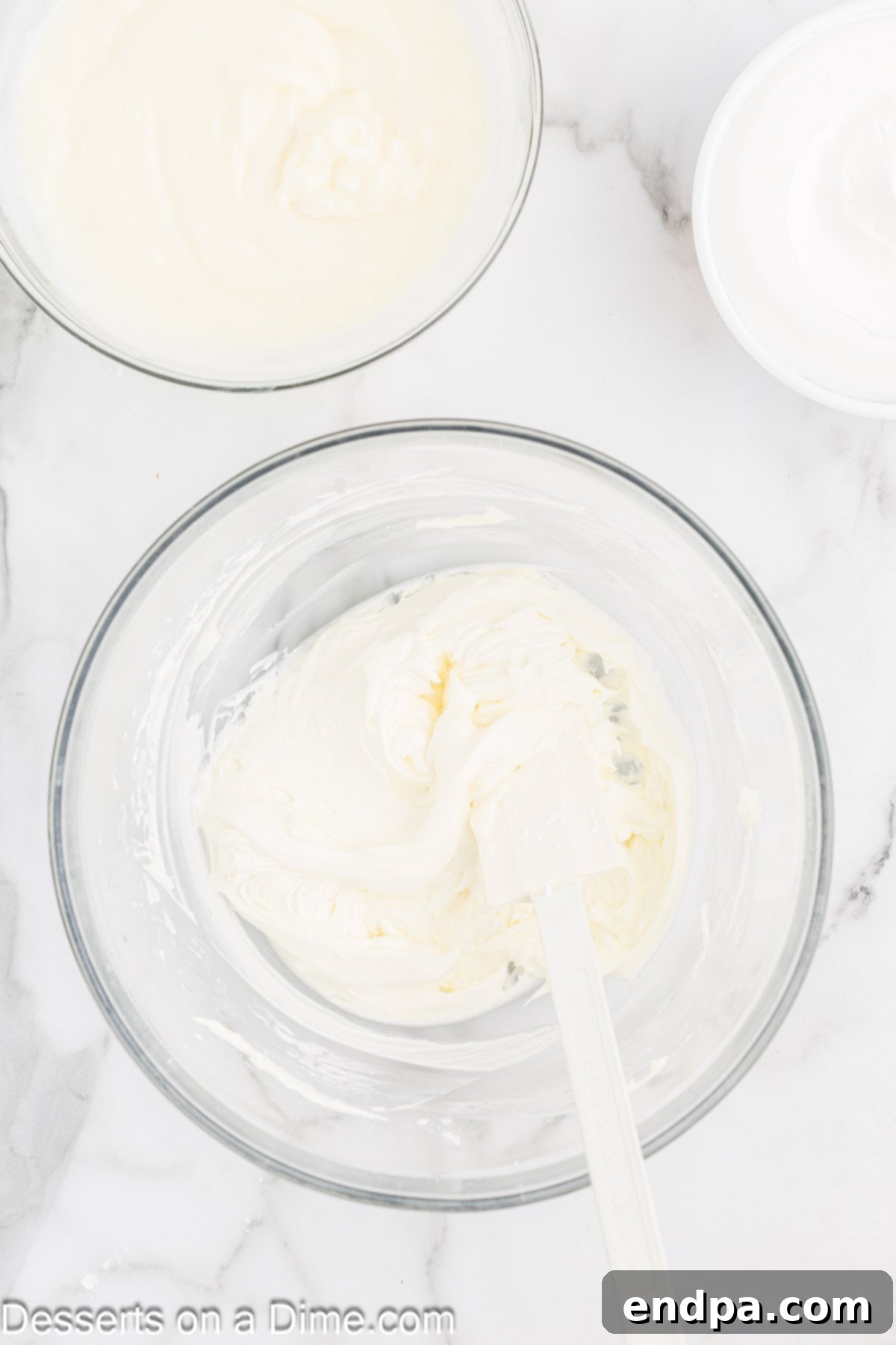 Separate mixing bowl with softened cream cheese being beaten until fluffy.