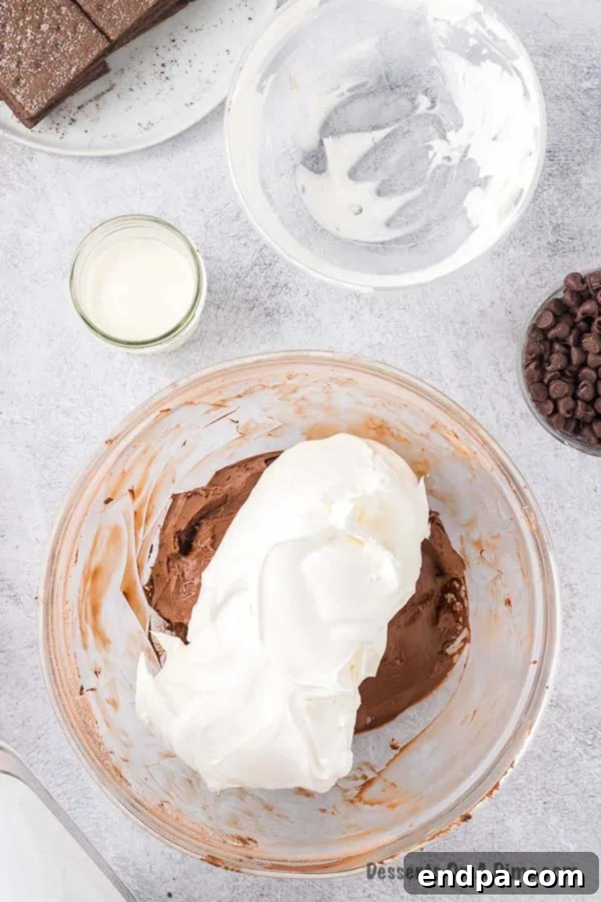 Whipped cream being gently folded into the cream cheese mixture in a bowl.