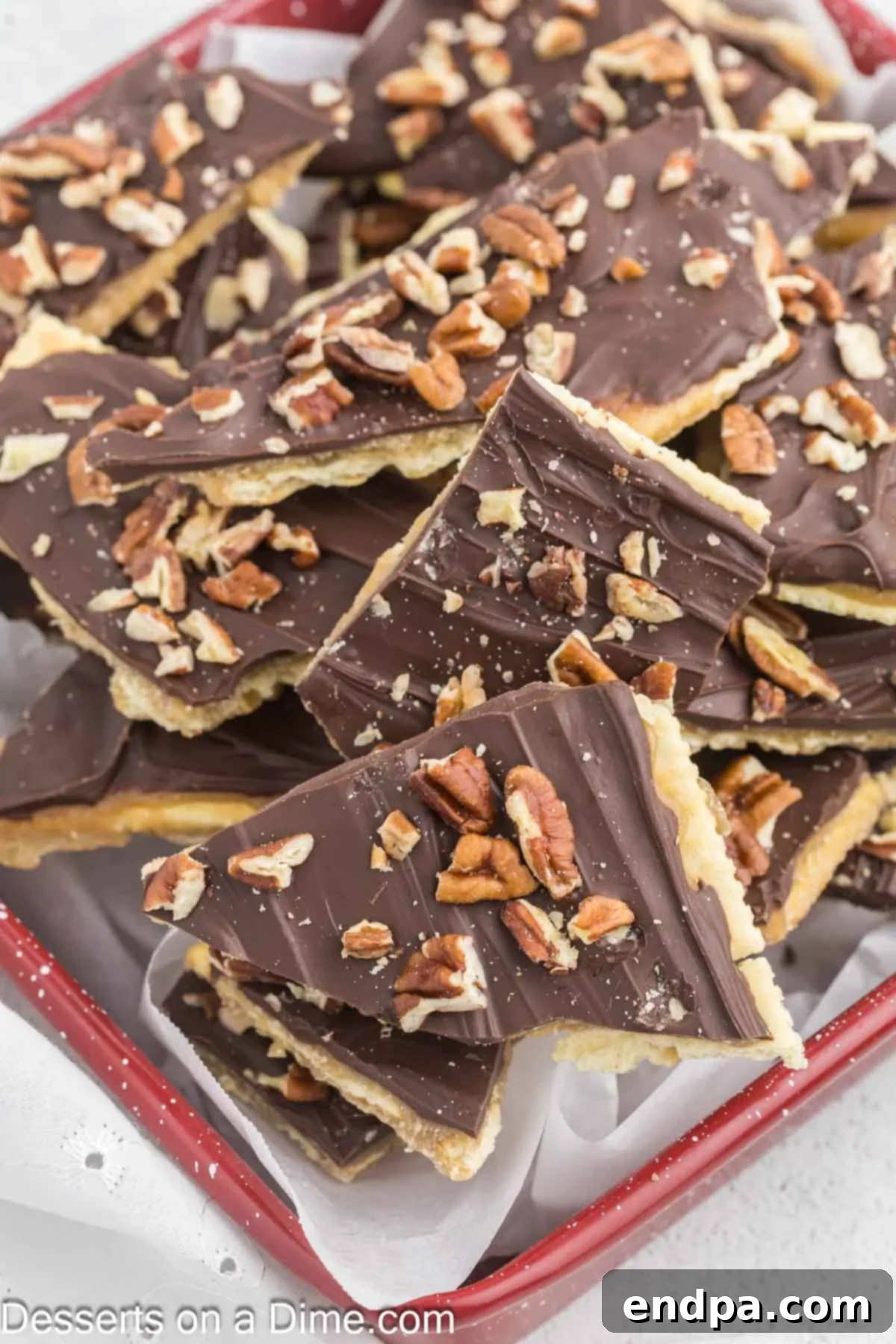 Sweet and Salty Toffee Bark 2 Crispy Saltine Toffee broken into irregular, tempting pieces on a serving platter, showcasing layers of cracker, golden toffee, and dark chocolate.