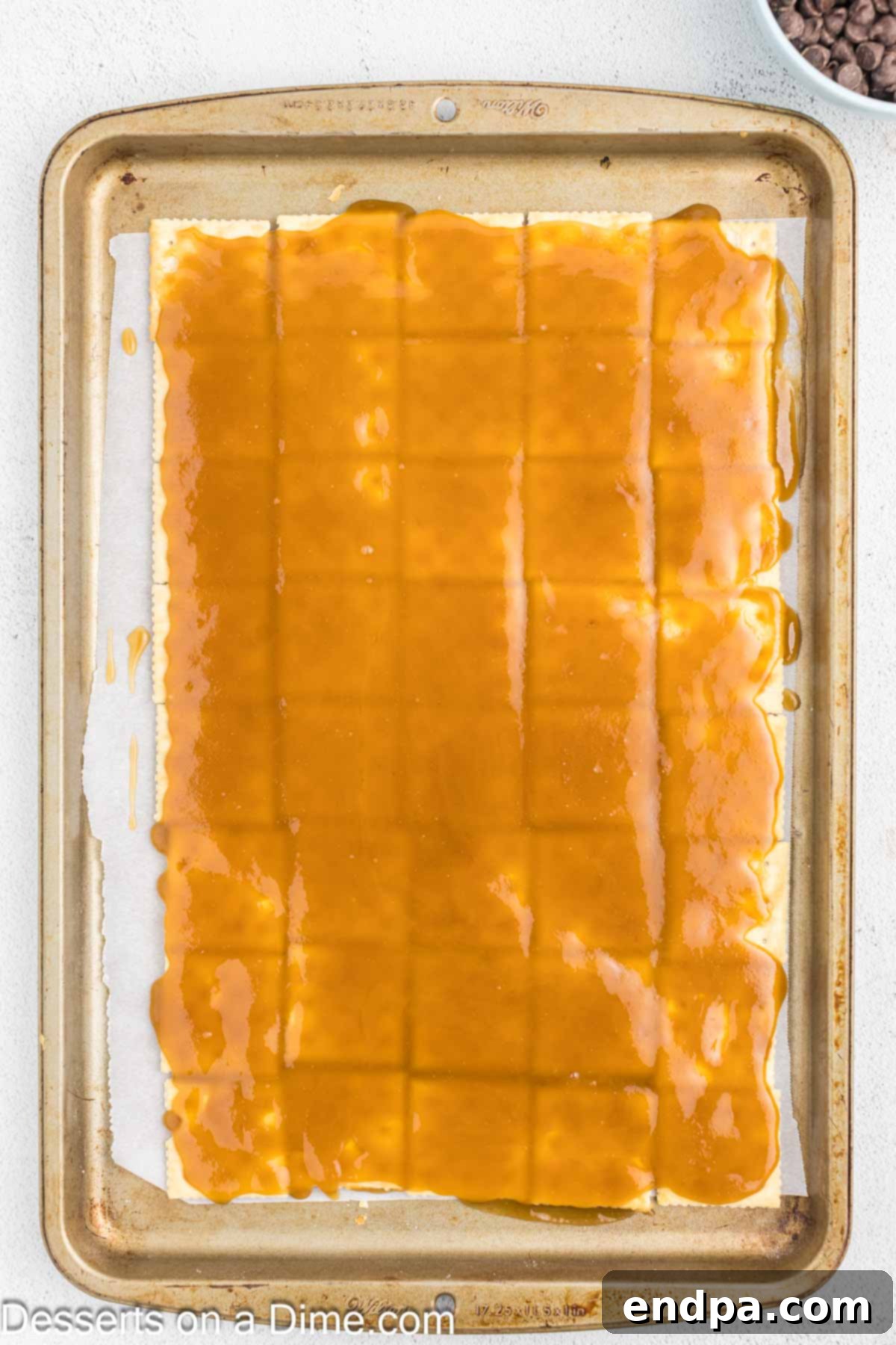 Sweet and Salty Toffee Bark 6 Hot, bubbly butter and brown sugar mixture being poured and spread evenly over the layer of saltine crackers.